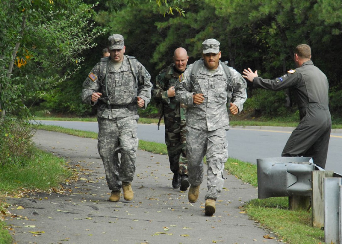Master Sgt. Korie Gavin, 113 SFS Phoenix Raven deputy program manager (second from left), is given motivation from Sergeant Atkinson (right), at the finish line of the road march.  Sergeant Gavin came in with a run time of 3 hours and 52 minutes while attempting to obtain  German Armed Forces, Troop Duty Proficiency Badge.   (USAF photo by Tech. Sgt. Adrianne M. Wilson)
