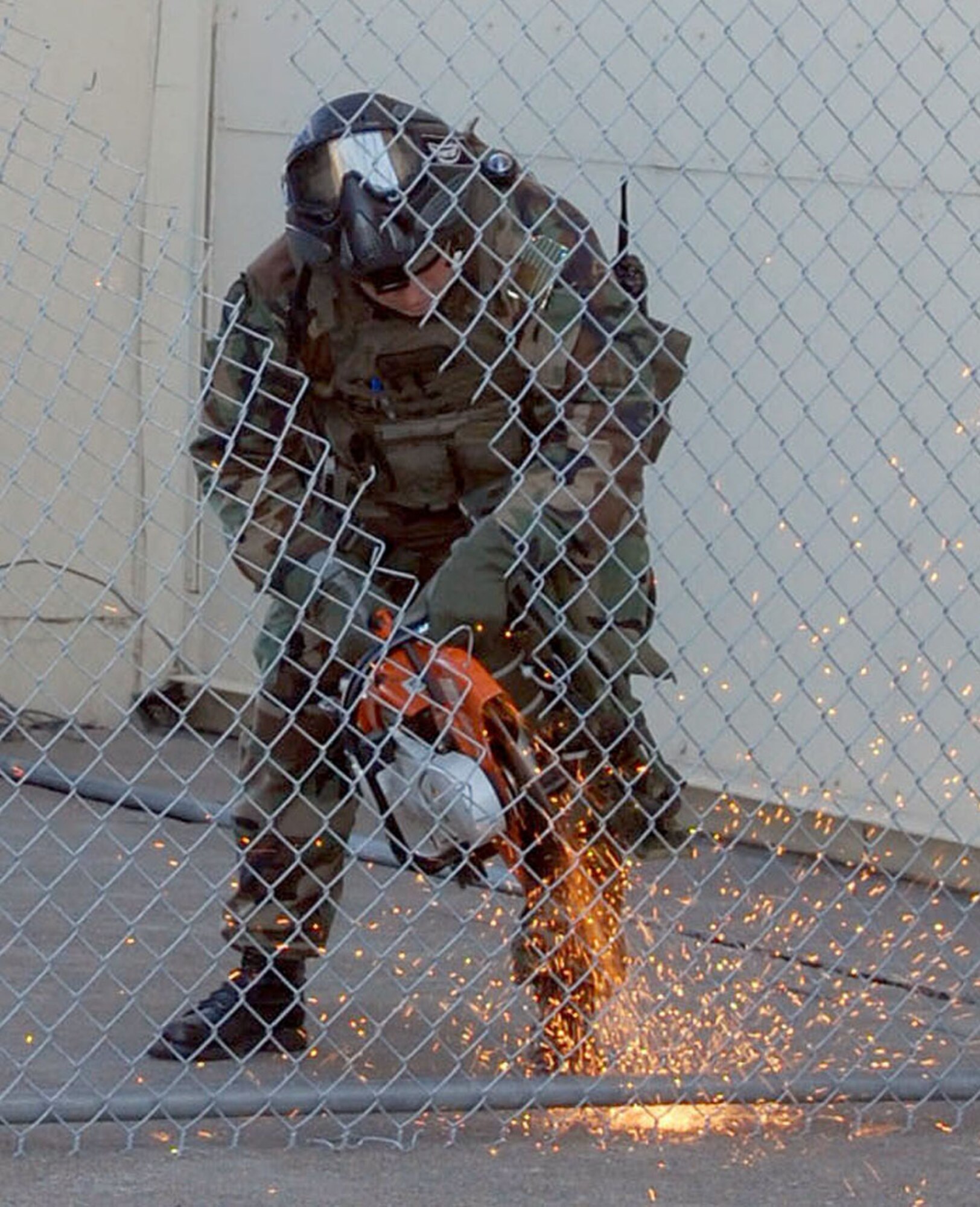 Senior Airman Jeffrey Baumgartner, 341st Security Forces Group Tactical Response Force member, cuts through a chain link fence with a K-12 breach saw for his team’s entry into the base’s new close-quarters battle center Sept. 30. 341st SFG personnel volunteered hundreds of hours to plan and construct the training facility.  (U.S. Air Force photo/Senior Airman Eydie Sakura)