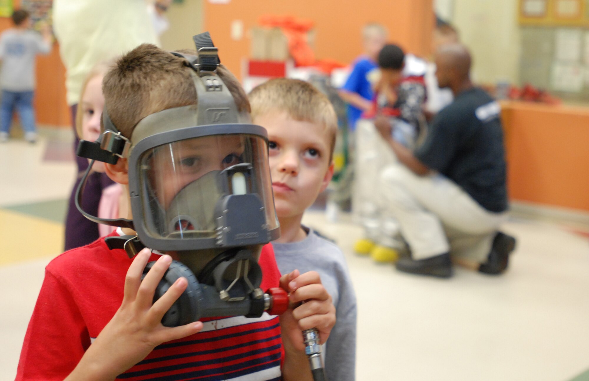 MCCONNELL AIR FORCE BASE, Kan. -- Tyler Morkin, in face mask, son of Tech. Sgt. Max Morkin and wife Kathy, and Mathias Holtorf, son of Staff Sgt. Tim Holtorf and wife Brenda, learn about how the mask keeps firemen able to breath while battling fires and smoke, Oct. 6, at the McConnell School Age Program. (Photo by Airman 1st Class Jessica Lockoski)