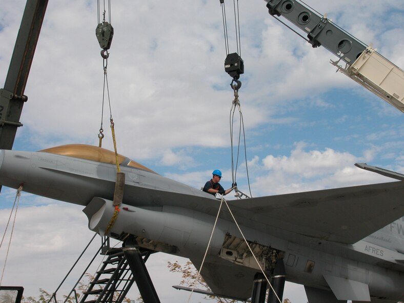 Tech. Sgt. Andrew Huff of the 466th Aircraft Maintenance Unit secures ropes around the F-16 static display that graced the former 419th Fighter Wing headquarters building. About 20 wing personnel helped remove the jet from its pedestals Oct. 2. The aircraft will be restored over the course of several months and moved to its new location closer to the new 419th and 388th Fighter Wings headquarters. (U.S. Air Force photo/Bryan Magaña)