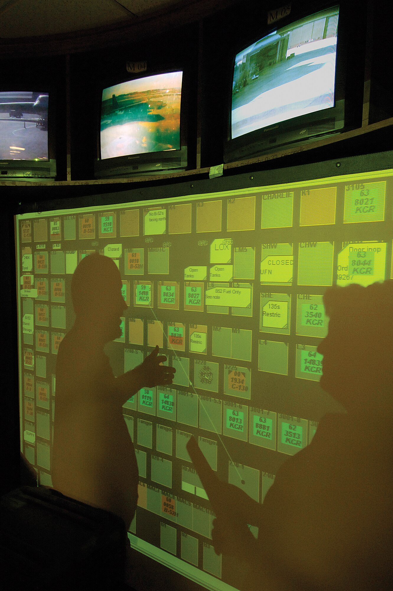 Not a plane moves  at Tinker without its movement and work documented in the 76th Maintenance Wing’s Maintenance Operations Center in Bldg. 3001.  Staffed around the clock, controllers use a wall of monitors and a board of blinking, moving squares to document aircraft work and control access to ramp areas.  Lead Frank Stangl and controller Mary Briscoe begin their night on the swing shift. (Air Force photo/Margo Wright)