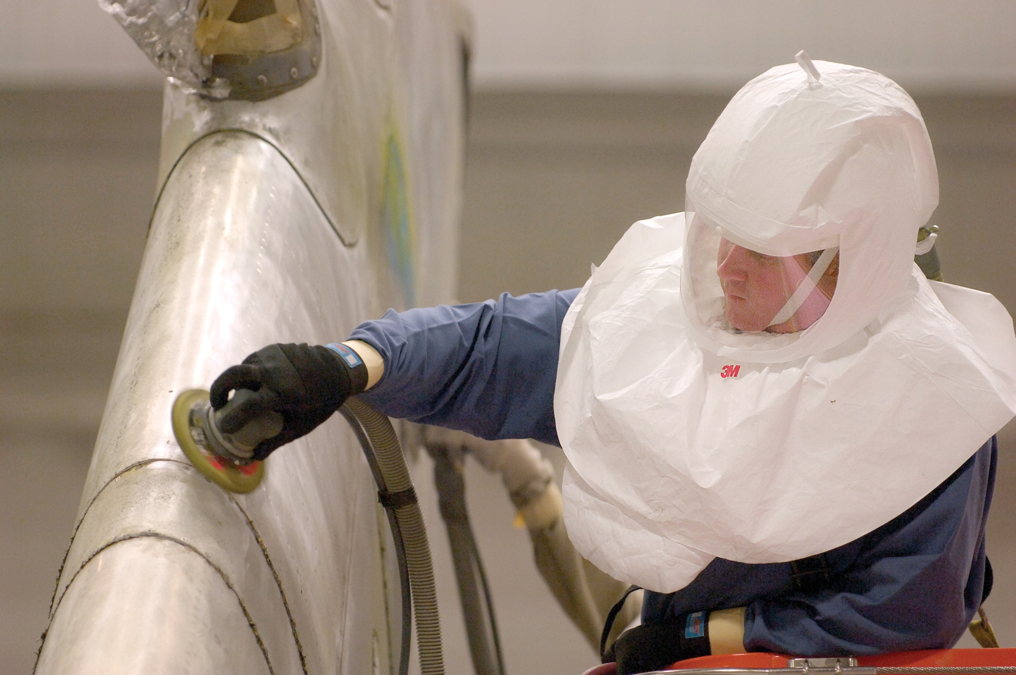 Anthony Hunt scuff sands a KC-10 vertical, 60 feet high in the Corrosion Control Facility hangar, Bldg. 2280.  Aircraft are worked non-stop by each shift as they are depainted, prepared and repainted by crews of the 76th Aircraft Maintenance Group.  Mr. Hunt is used to swing shift work and has been depainting and painting aircraft for four years.  Working at Tinker is a family tradition and he’s quick to offer praise for his good job and the safety measures ensured to him in his job. (Air Force photo by Margo Wright)