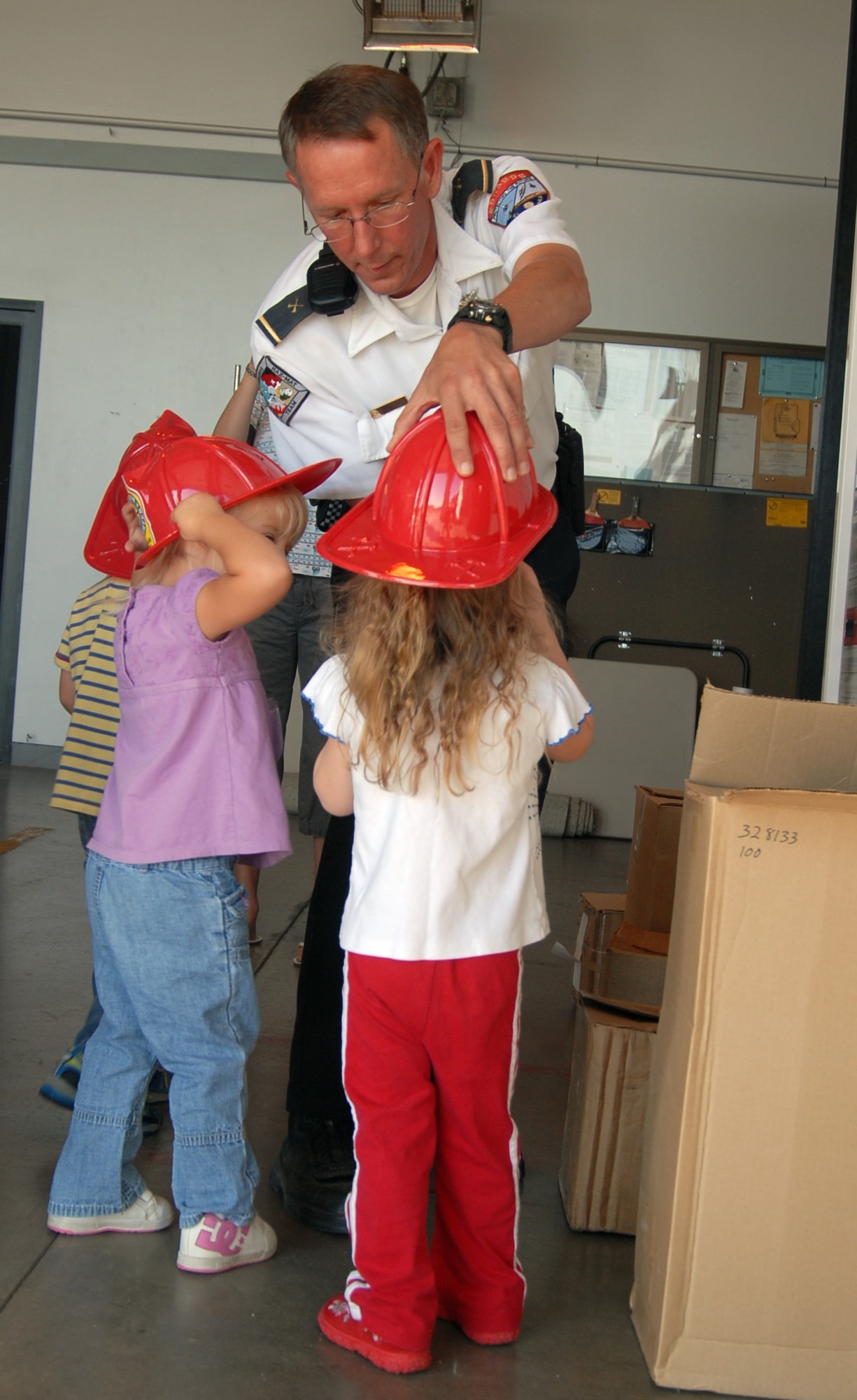 Kurt Stranick, fire department investigator, puts a platic firefighter's hat on an Edwards child during a Fire Prevention Week presentation at fire station II Oct. 9. The Fire Prevention Week kicked off Sept. 5 with a Fire Department Booster Club Annual Charity golf tournament at the Muroc Lake Golf Course here. The week concluded with a parade Oct. 11. (Air Force photo by Senior Airman Julius Delos Reyes)
