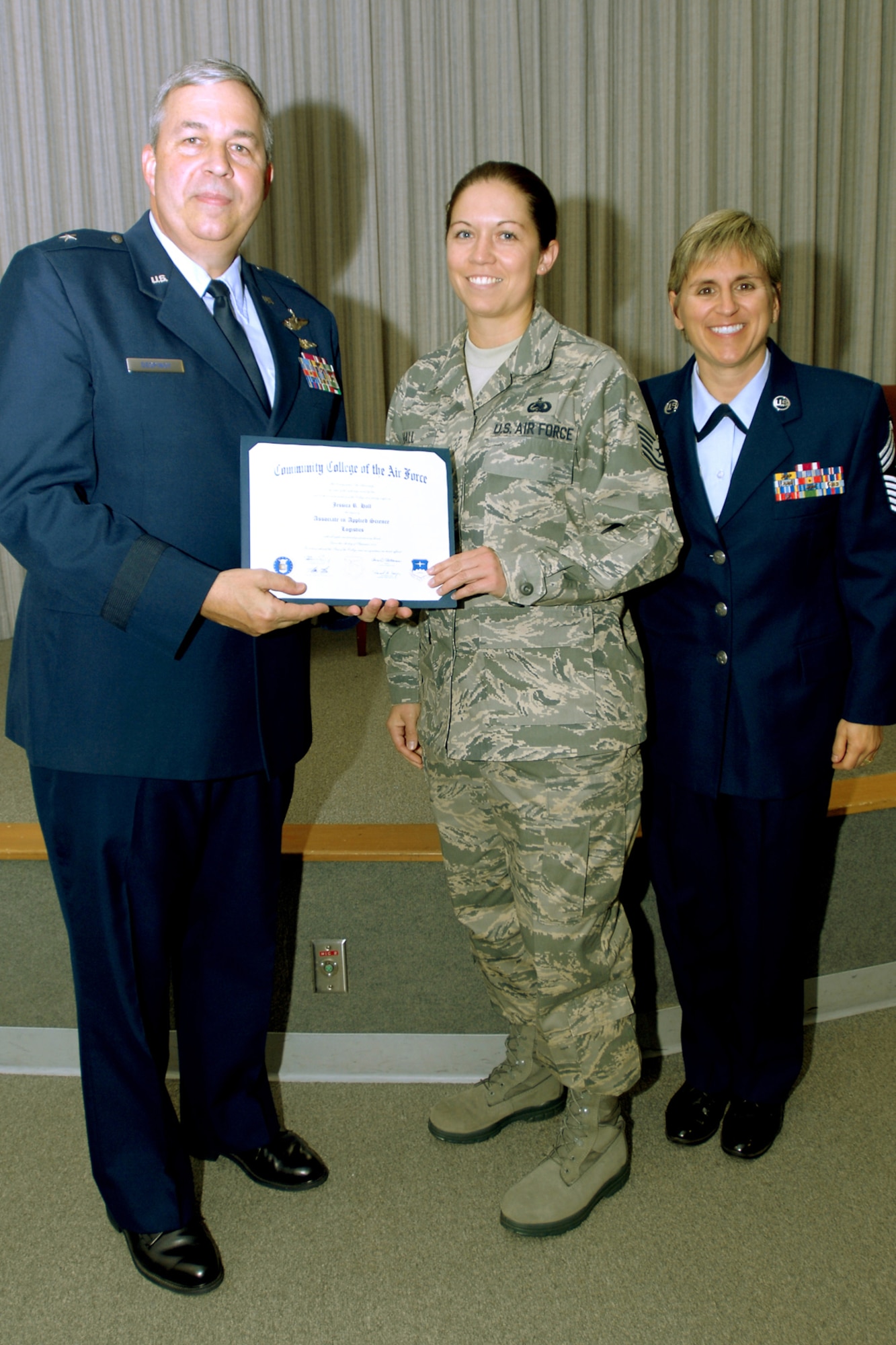 GRISSOM AIR RESERVE BASE, Ind., -- Tech. Sgt. Jessica Hall, 434th Logistics Readiness Squadron supply management journeyman, poses for a photo during a recent Community College of the Air Force graduation ceremony. Sergeant Hall graduated with a degree in logistics. Pictured alongside Sergeant Hall are Brig. Gen. Dean Despinoy, 434th Air Refueling Wing commander, and Chief Master Sergeant Peri Rogowski, 434th ARW command chief. CCAF is the largest community college in the world and is the only community college in the Department of Defense. Each year about 1.6 million semester hours are earned in CCAF classrooms. (U.S. Air Force photo/Staff Sgt. Mark Orders-Woempner)