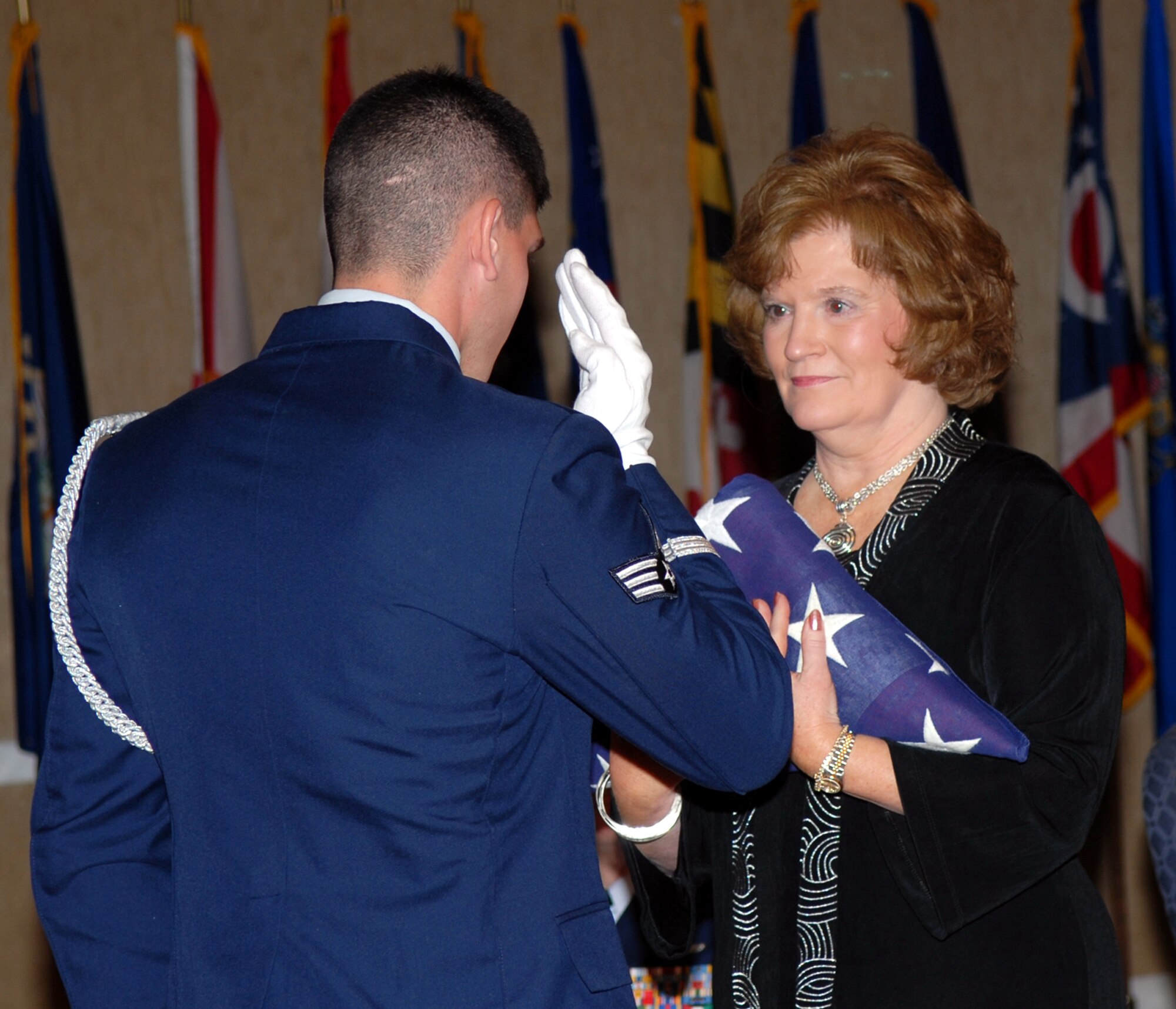 Martha Rodgers, 14th Flying Training Wing Installation Deployment Officer, is presented a flag in honor of her 39 years of federal service by honor Guard member Senior Airmen Matthew Terkay at her retirement  ceremony on Oct. 3. (U.S. Air Force photo)