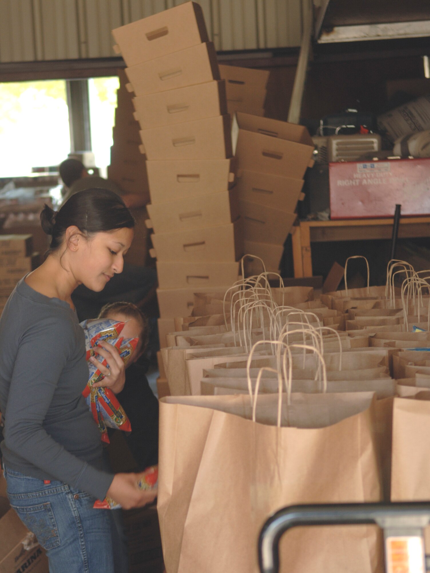 GRAND FORKS AIR FORCE BASE, N.D.- Senior Airman Kimberly Duenas, 319th Medical Group, gathers packages of food to be placed in bags that will eventually be delivered to the elderly as part of the Red River Valley Community Action’s commodity supplemental food program. More than 60 base Airmen and family members have donated time to the project, which helps more than 600 elderly citizens monthly. (U.S. Air Force photo/Staff Sgt. J. Paul Croxon) 