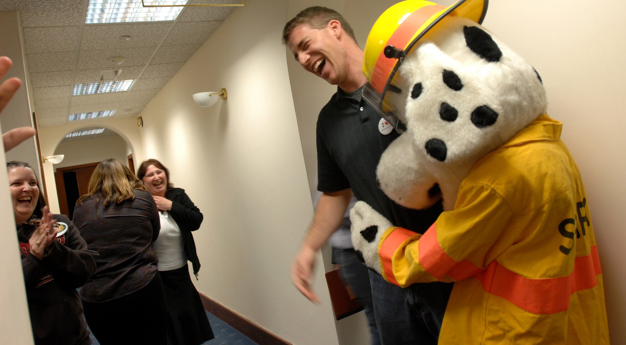 To boost morale, Sparky the Fire Dog visits the finance wing of the 100th Air Refueling Wing headquarters building where he finds numerous 100th Comptroller Squadron budget analysts working hard to ‘closeout’ the fiscal year 2008 accounting records, Sept. 30, 2008. Amongst many chuckles, Sparky hugs the budget officer Capt. Joshua Weed as a gesture of moral support. (Air Force photo by Master Sgt. Tracy L. DeMarco)
