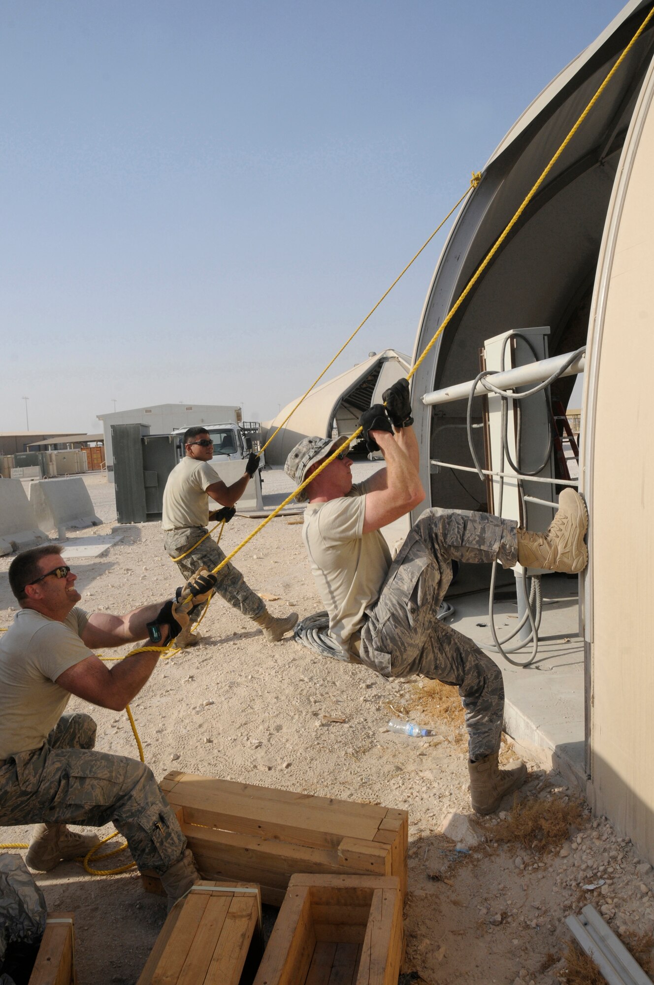 Maj. Steven Blake, commander, 1st Expeditionary Rapid Engineer Deployable Heavy Operational Repair Squadrons Engineer (RED HORSE) Group, leads a team repairing a temporary structure October 8, 2008.  Major Blake muscles the rope with the assistance of Tech. Sgt. Mathew Levesque, 1 ERHG, while Staff Sgt. Juan Dominguez, 1 EHRG, pulls on a rope attached to the opposite side of the new material at an undisclosed air base in Southwest Asia. RED HORSE members construct runways and shelters throughout the entire area of responsibility in support of Operations Iraqi and Enduring Freedom and Joint Task Force-Horn of Africa.  Major Blake is a native of Dallas, Texas.  Sergeant Levesque hails from Auburn, Maine, and Sergeant Dominquez is from Del Rio, Texas. All are deployed from Hurlburt Field, Fla. (U.S. Air Force photo by Staff Sgt. Darnell T. Cannady/Released)