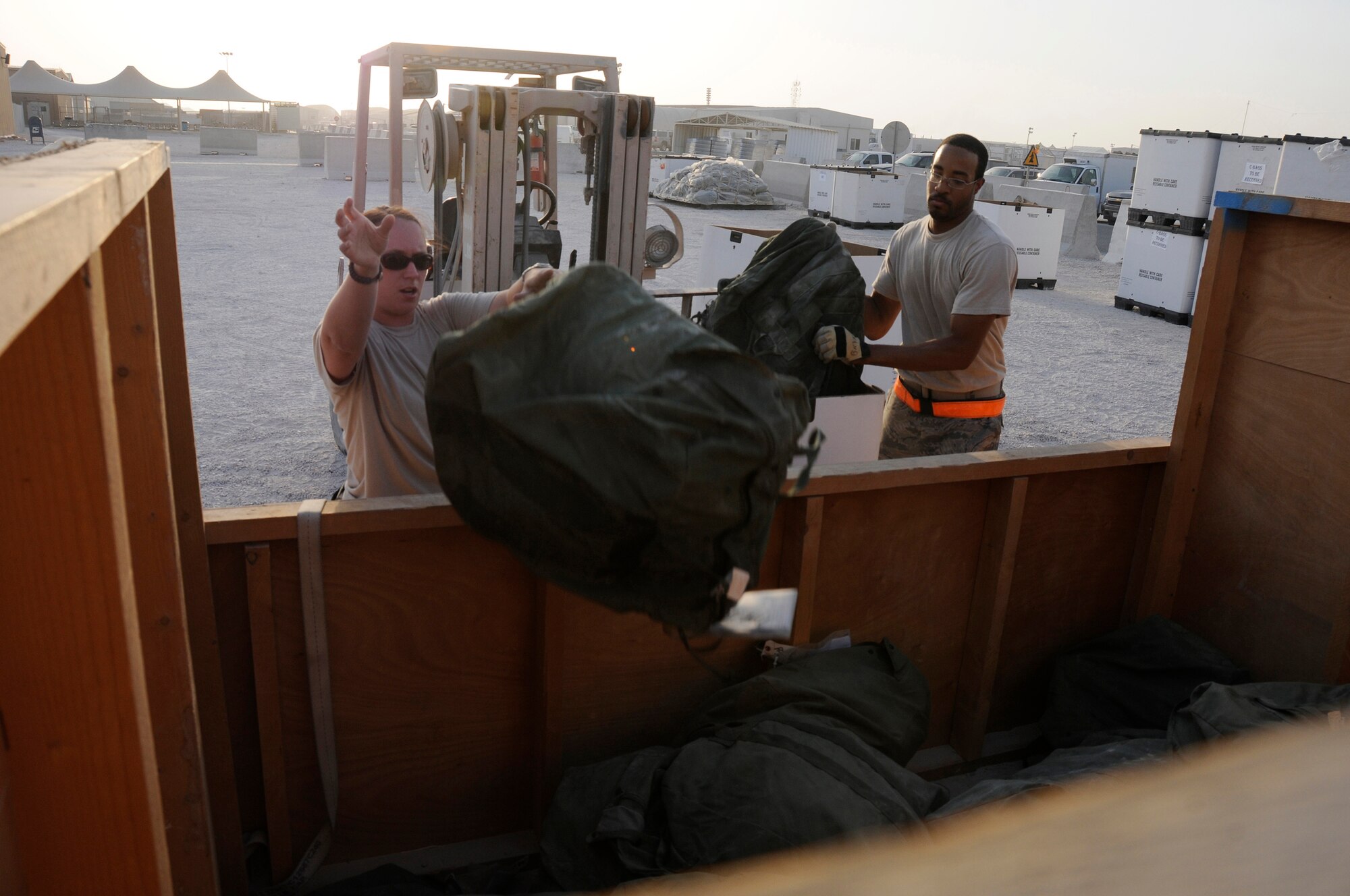 Staff Sgt. Beth Sprowls, and Senior Airman Jerome Bryant, 379th Expeditionary Logistics Readiness Squadron, toss C-Bags into a storage bin October 8, 2008.  The C-bag contains sealed chemical gear, including overgarment suits, gloves, boots, gas mask canisters and M-291 decontamination kits.  The bags are returned items from Airmen rotating back to home stations after completing their deployments.  The bags are sorted by size and stored here at an undisclosed air base in Southwest Asia.  Sergeant Sprowls, a native of Herrings, N.Y., and Airman Bryant, hailing from Little Rock, Ark., are both deployed from Shaw Air Force Base, S.C., in support of Operations Iraqi and Enduring Freedom and Joint Task Force-Horn of Africa.  (U.S. Air Force photo by Tech. Sgt. Michael Boquette/Released)