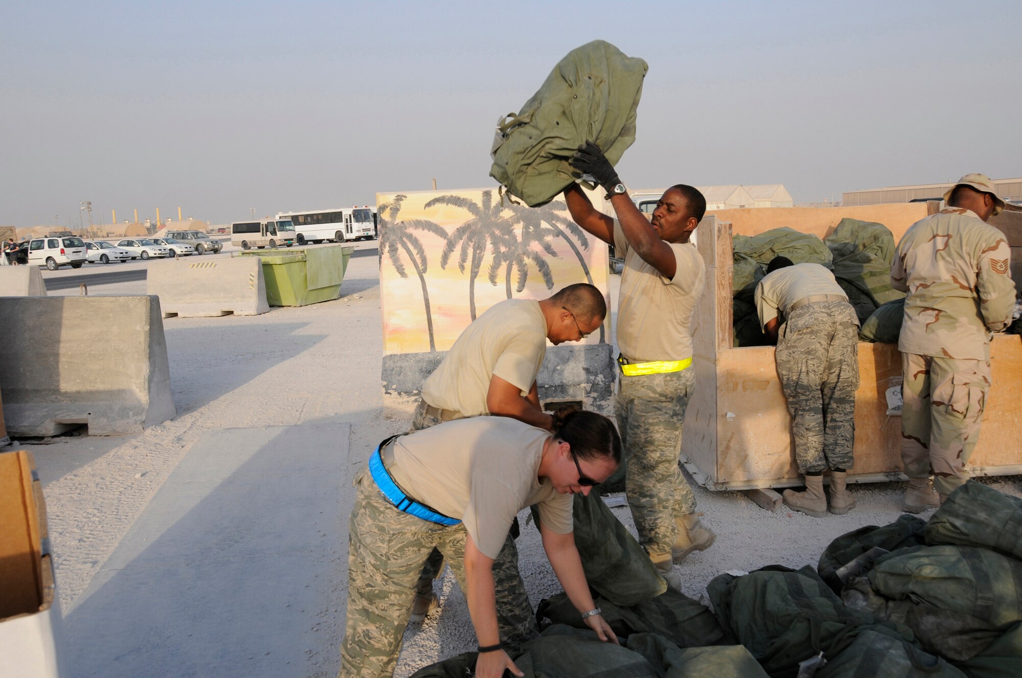 Airman 1st Class Rilwan Baruwa gives a high toss of a C-Bag into a temporary box while Staff Sgt. Beth Sprowls and Airman 1st Class Charlton Ysip grab bags to add to the box October 8, 2008.  All three are assigned to the 379th Expeditionary Logistics Readiness Squadron supporting Operations Iraqi and Enduring Freedom and Joint Task Force-Horn of Africa.  The C-bag contains sealed chemical gear, including overgarment suits, gloves, boots, gas mask canisters and M-291 decontamination kits.  The bags are returned items from Airmen rotating back to home stations after completing their deployments.  The bags are sorted by size and stored here at an undisclosed air base in Southwest Asia.  Sergeant Sprowls, a native of Herrings, N.Y., and Airman Baruwa, from Chicago Ill., are both deployed from Shaw Air Force Base, S.C.  Airman Ysip is from Pittsburg, Calif., and is deployed from Luke Air Force Base, Ariz.  (U.S. Air Force photo by Tech. Sgt. Michael Boquette/Released)