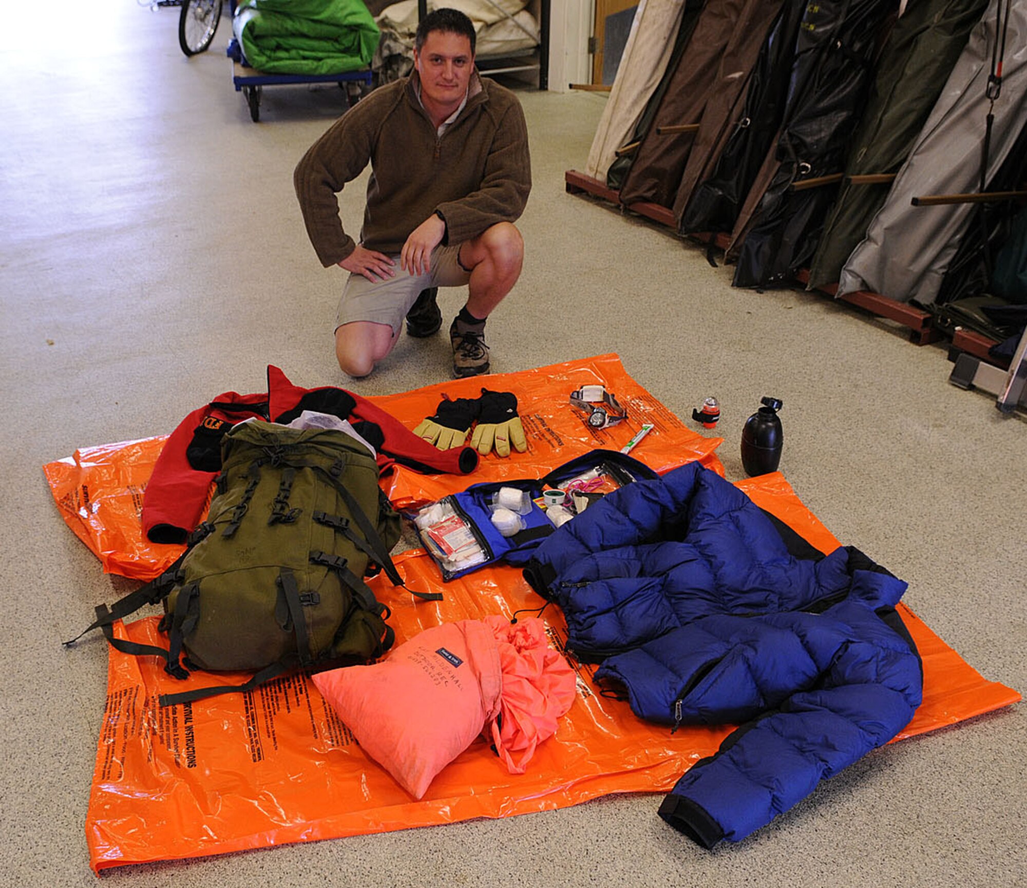 Dave Wainwright, 100th Force Support Squadron Outdoor Recreation director, and qualified mountain guide, shows off the survival equipment he and three British firefighters, Alan Coldwell, Chris Gould and Jerry Myles, took with them on the Three Peaks Challenge Oct. 2 and 3. Using this equipment, the four men saved another man's life when they found him alone and unconscious at the top of Mount Snowdon. the man was suffering from hypothermia and frostbite, and the men from RAF Mildenhall put him in their spare clothes and jackets and wrapped him in the orange bivi bags to keep him warm while they called the North Wales Police and mountain rescue. (U.S. Air Force photo by Staff Sgt. Jerry Fleshman)