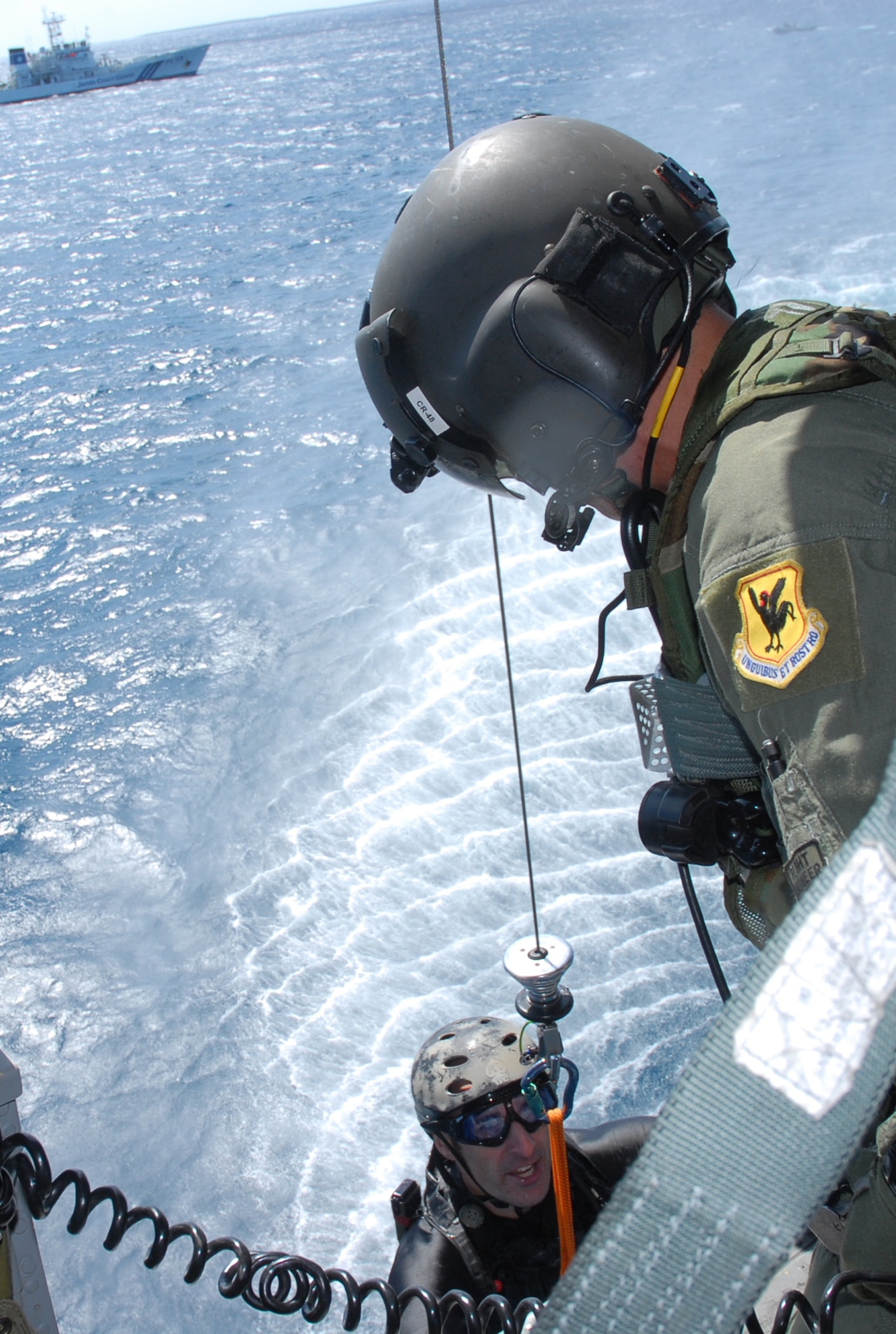 Staff Sgt. Jonathan Courtright, a Pararescue Airman  assigned to the 31st Rescue Squadron is hoisted up onboard an HH-60 by Master Sgt. Ernest Garcia, flight engineer assigned to the 33rd Rescue Squadron, after rescuing a downed F-15 pilot as part of a crisis management exercise off the coast of Okinawa, Oct. 8, 2008. Members of the 18th Wing and Japanese Coast Guard rehearsed response procedures for a simulated over the water aircraft accident. (U.S. Air Force photo/Staff Sgt. Chrissy Best)
