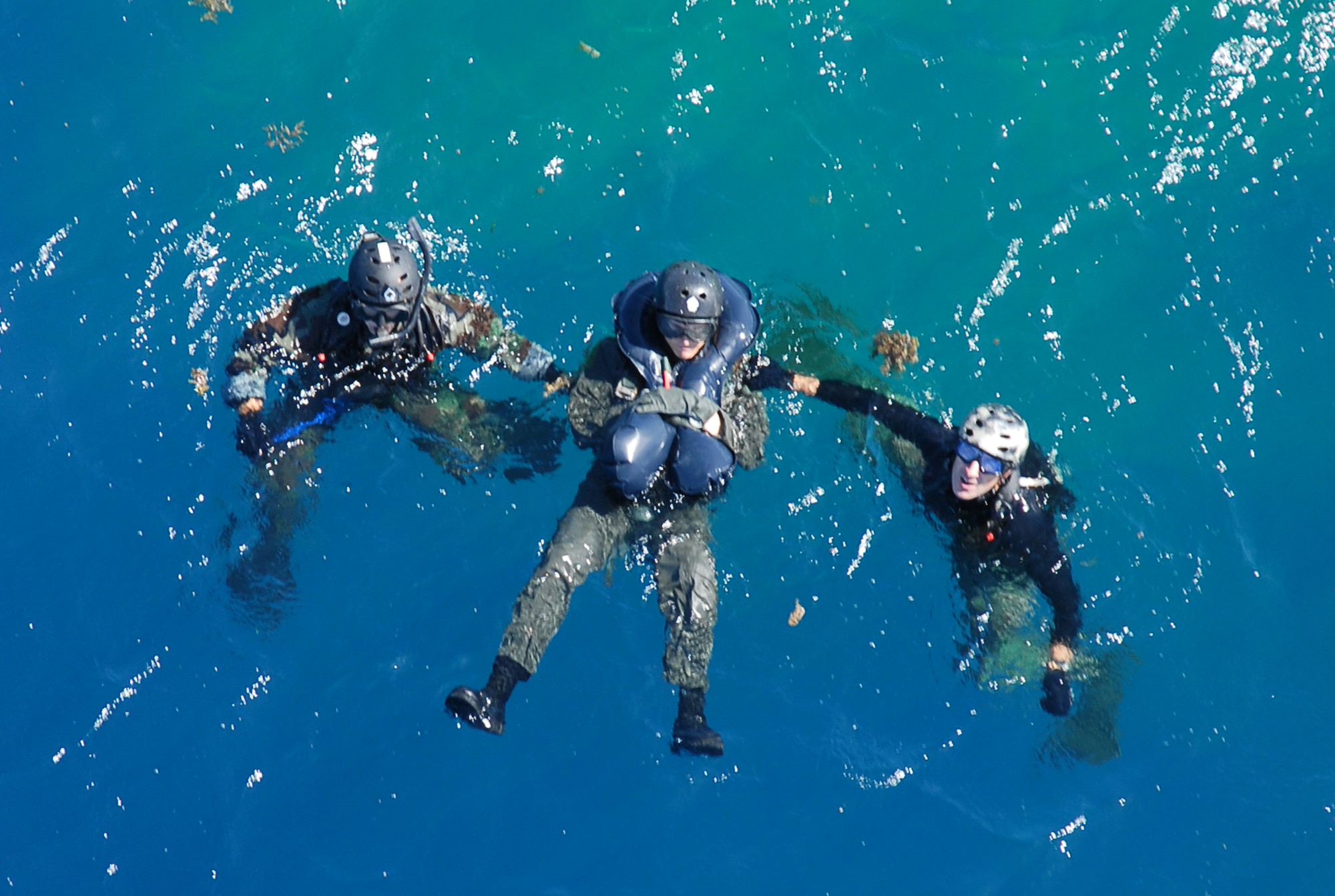 Senior Airman Oliver Smith, (left) and Staff Sgt. Jonathan Courtright, (far right) both from the 31st Rescue Squadron, secure a downed F-15 pilot and signal to the flight engineer  to hoist them onboard an HH-60 during a crisis management exercise off the coast of Okinawa Oct. 8, 2008. Members of the 18th Wing and Japanese Coast Guard  rehearsed response procedures for a simulated over the water aircraft accident. (U.S. Air Force photo/Staff Sgt. Chrissy Best)
