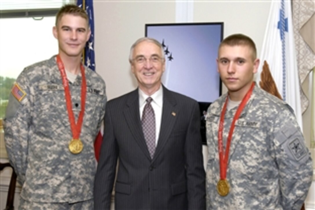 Deputy Defense Secretary Gordon England poses for a photo, in his Pentagon office, Oct. 9, 2008, with two Army gold medalists from the 2008 Summer Olympic Games in Beijing, China.  Spc. Glenn Eller, left, won his gold medal for trap shooting. Spc. Vincent Hancock earned the gold in skeet shooting. Both men, members of the U.S. Army Marksmanship Unit, have competed in numerous events around the globe.