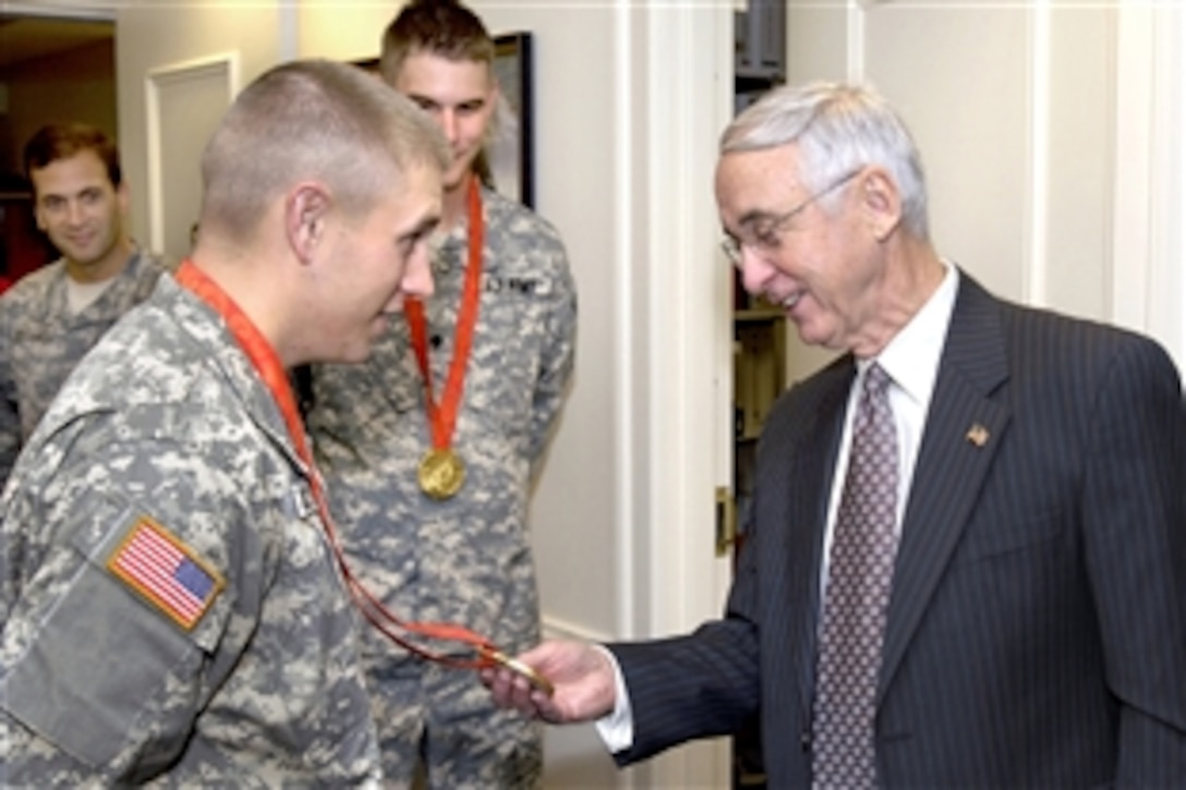 Deputy Defense Secretary Gordon England admires the Olympic Gold Medal won by Army Spc. Vincent Hancock during the recent Beijing games for his remarkable skill at skeet shooting. Joining Hancock for the Oct. 9, 2008, visit with England in his Pentagon office, is fellow Army Marksmanship Unit team mate Spc. Glenn Eller, who was the gold medalist in trap shooting. Both men are considered to be the No. 1 ranked shooter in the world for their particular discipline. 