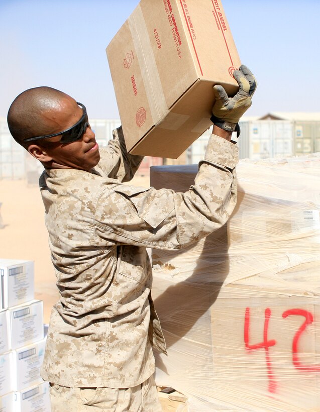 Pfc. Albelardo Flores, a basic warehousemen with 1st Light Armored Reconnaissance Battalion, Regimental Combat Team 5, lifts a box from a pallet in order to move it into a storage container at Camp Korean Village, Iraq. Supply Marines of 1st LAR Bn. are responsible for about $5 million worth of gear and other inventory items.::r::::n::