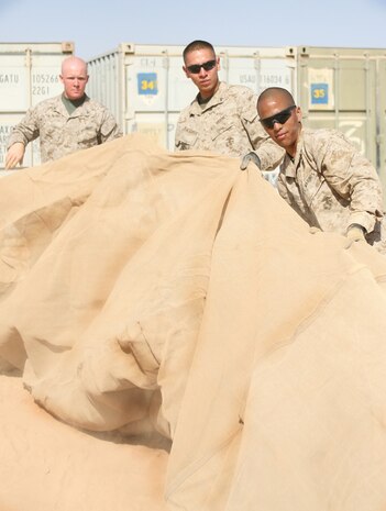 Lance Cpl. Joseph C. Sharp, Pfc. Xavier Blackdeer and Pfc. Albelardo Flores (left to right),all with 1st Light Armored Reconnaissance Battalion, Regimental Combat Team 5, gather up a tent to be moved out to 1st LAR Bn.â??s operations area. Supply Marines with 1st LAR Bn. are responsible for fielding gear from more than 300 different outlets to fill the battalionâ??s needs.::r::::n::