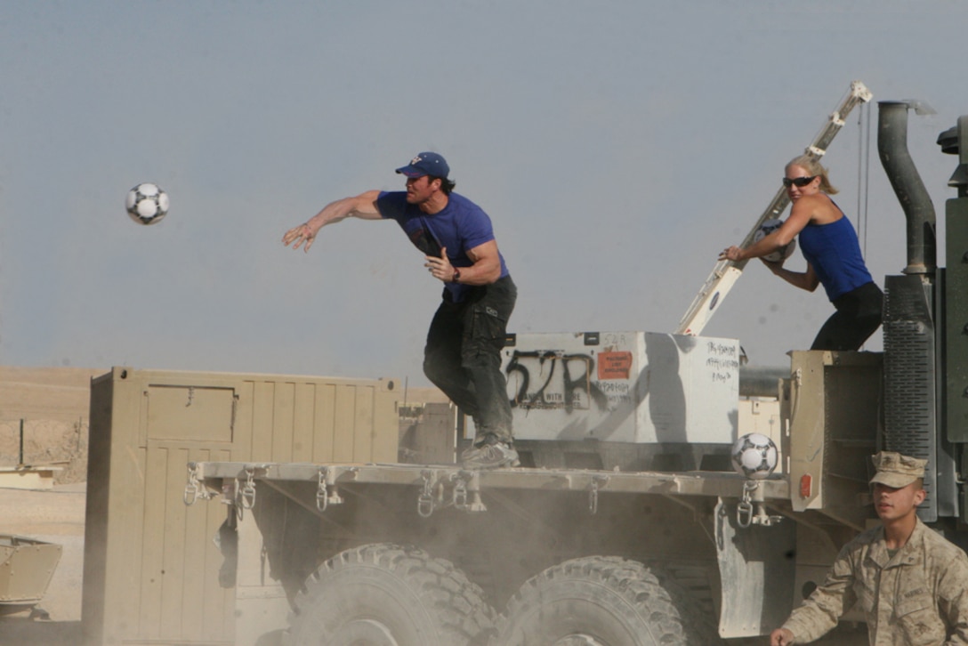 Titan and Venom, gladiators from the TV series "American Gladiators," launch soccer balls at assaulting Marines, attempting to hit them before they reach their goal near the vehicle. The gladiators had a protective barrier made of wood pallets until Sgt. Damien Robinson, administration non-commissioned officer in charge with Task Force 2nd Battalion, 2nd Marine Regiment, Regimental Combat Team 5, demolished it with a single well aimed throw.