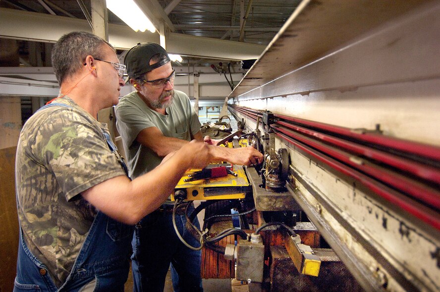 Greg White (left) and Robert Eisenbrey repair tools and machines necessary to keep production flowing Oct. 2 at Tinker Air Force Base, Okla. The 76th Maintenance Wing Support Group plant management team work to repair a transporter that lifts and moves parts to several vats of cleaners. (U.S. Air Force photo/Margo Wright) 
