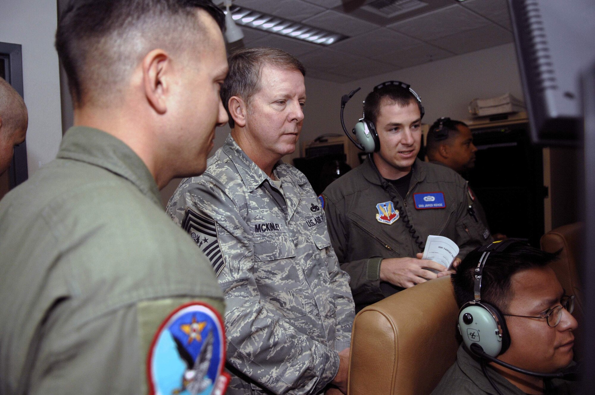 Master Sgt. Chris Vanderbilt (left) Senior Airman Jared Kehoe (right) and Staff Sgt. Bobby Vivar (seated) show Chief Master Sgt. of the Air Force Rodney J. McKinley MQ-1 Predator training operations Oct. 7 at Creech Air Force Base, Nev. Sergeant Vanderbilt is the 11th Reconnaissance Squadron operations superintendent, Airman Kehoe is an 11th RS sensor operator instructor, and Sergeant Vivar is a 11th RS sensor operator student. (U.S. Air Force photo/Airman 1st Class Stephanie Rubi) 

