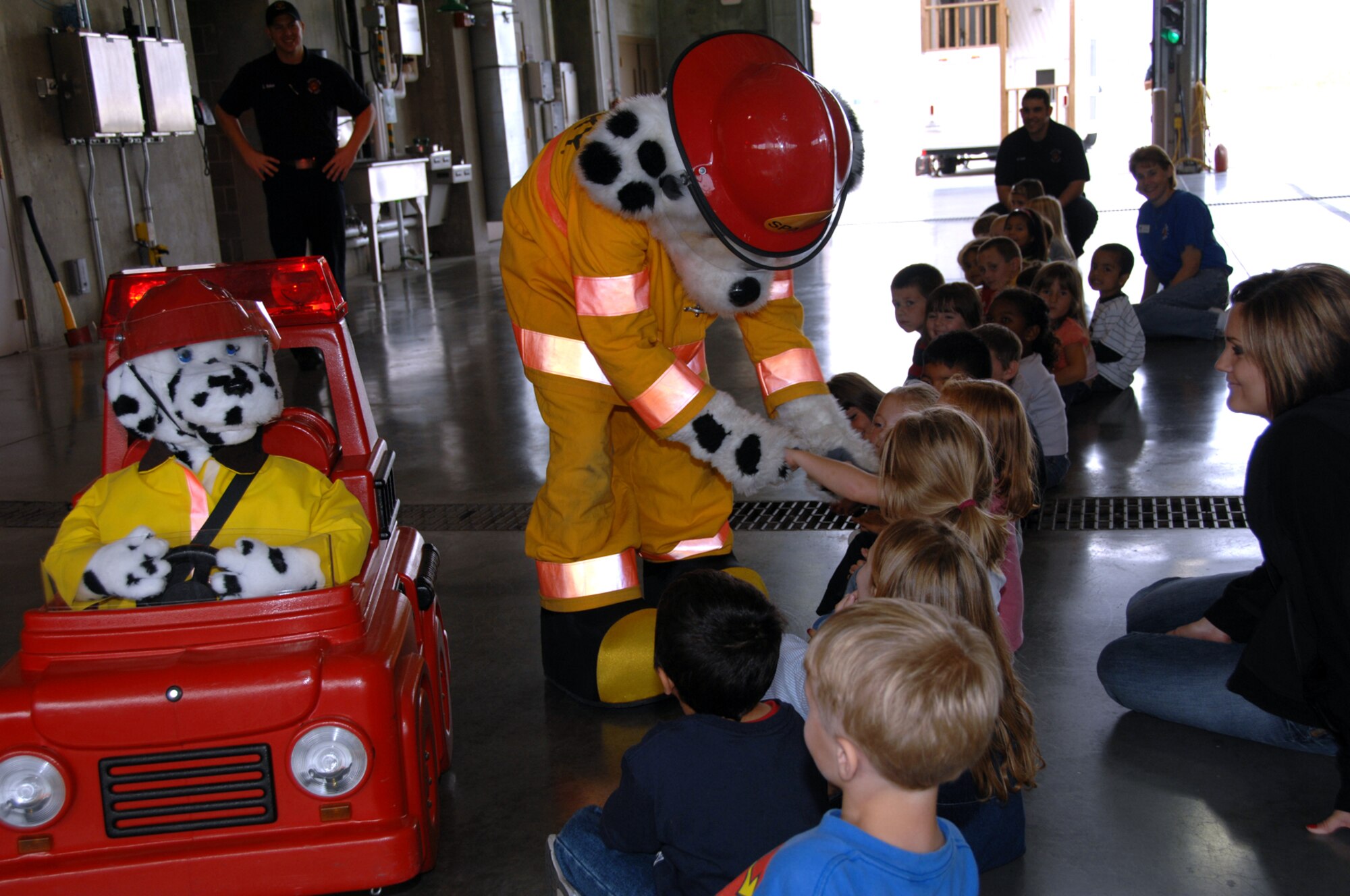 OFFUTT AIR FORCE BASE, Neb. -- Patches and his fire truck Pumper drive by to say “hi,” as Sparky the Firedog greets children from Birchcrest Elementary school during a field trip to the Offutt Fire Station Oct. 8 The Offutt Fire Station gave three to four tours a day to local schools this week as part of Offutt’s participation in National Fire Prevention Week. While at the fire station, students enjoyed fire safety videos, a demonstration of a firefighter in full gear including oxygen tank, a chance to go through the fire safety house during a simulated fire and a fire truck demonstrating the range of its water pumps. (U.S. Air Force Photo By Kendra Williams)