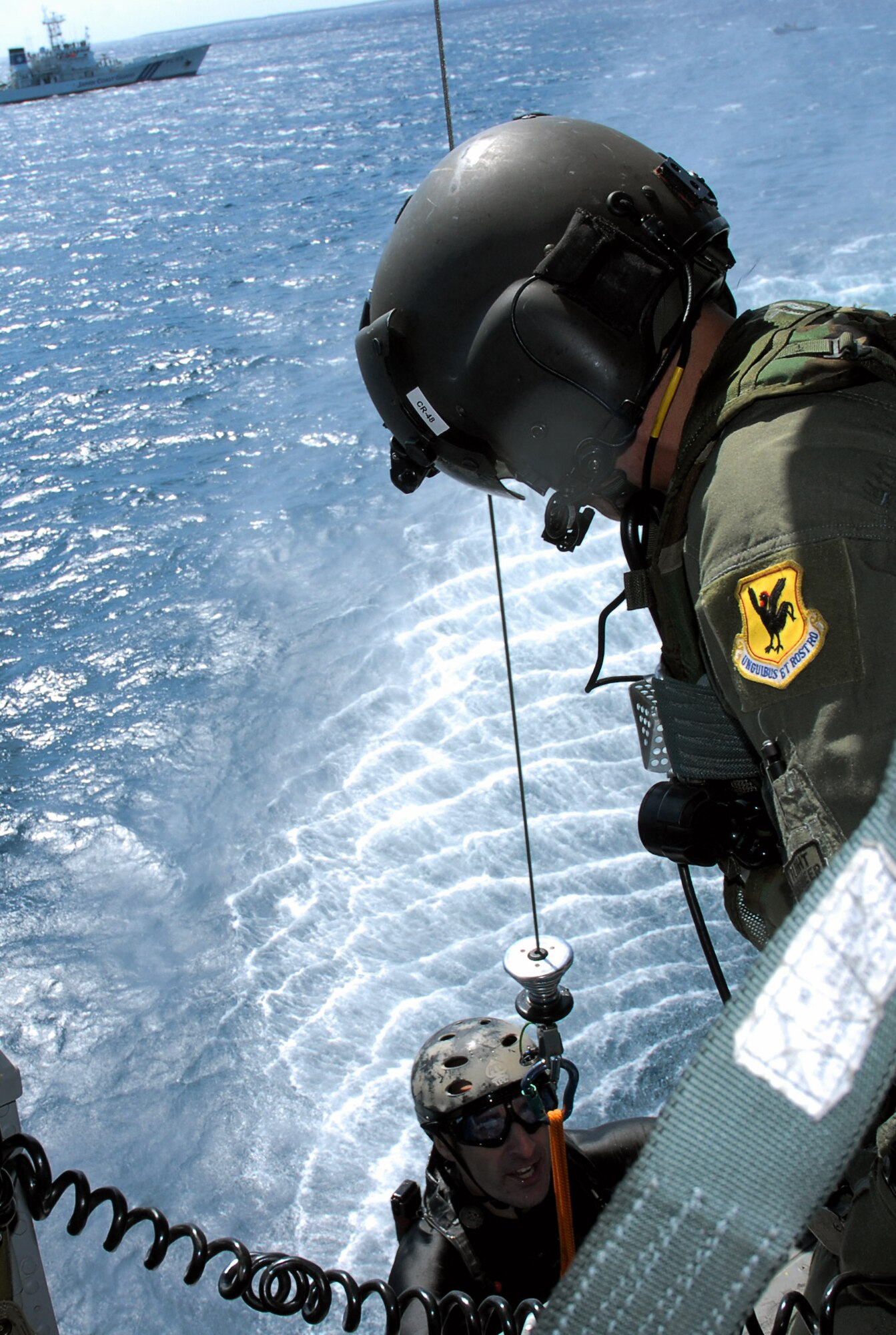 Staff Sgt. Jonathan Courtright is hoisted up onboard an HH-60G Pave Hawk by Master Sgt. Ernest Garcia after rescuing a downed F-15 Eagle pilot as part of a crisis management exercise Oct. 8 off the coast of Okinawa, Japan. Members of the 18th Wing from Kadena Air Base, Japan, and the Japanese coast guard rehearsed response procedures for a simulated over the water aircraft accident. Sergeant Courtright is a pararescue Airman assigned to the 31st Rescue Squadron, and Sergeant Garcia is a flight engineer assigned to the 33rd Rescue Squadron. (U.S. Air Force photo/Staff Sgt. Chrissy Best) 
