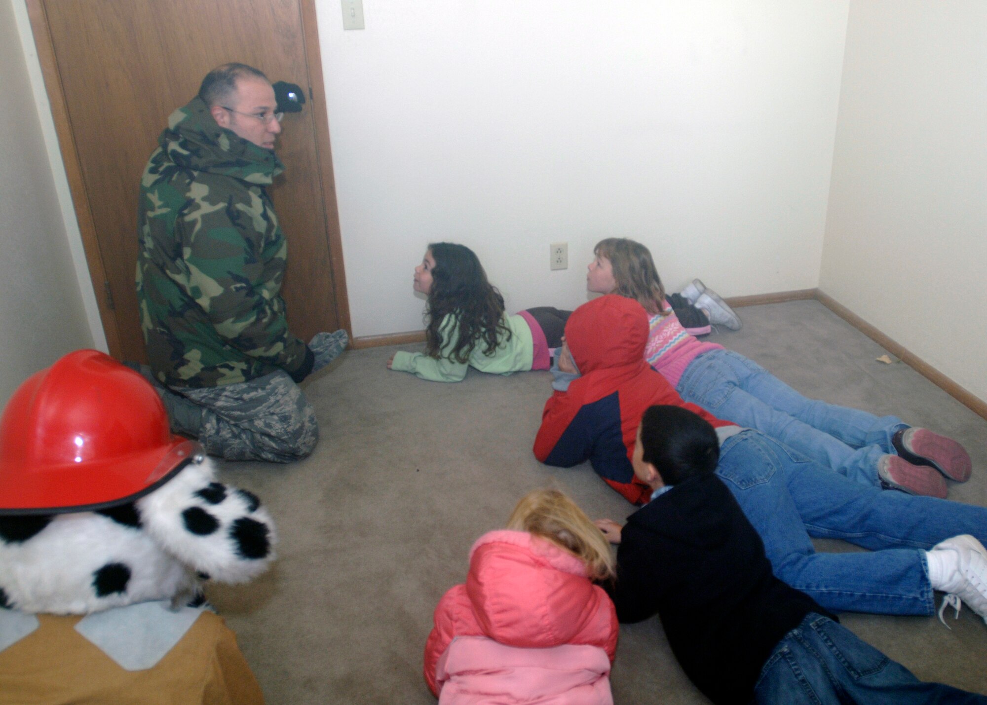 FAIRCHILD AIR FORCE BASE, Wash. – Tech. Sgt. Richard Galtieri, 92nd Civil Engineer Squadron assistant chief of fire prevention, and Sparky the Fire Dog teach kindergarten students from Michael Anderson Elementary School how to escape from their homes in the midst of a fire. Students were led through an empty house filled with simulated smoke and taught how to get out safely. (U.S. Air Force photo / Airman 1st Class Melissa Barnett)
