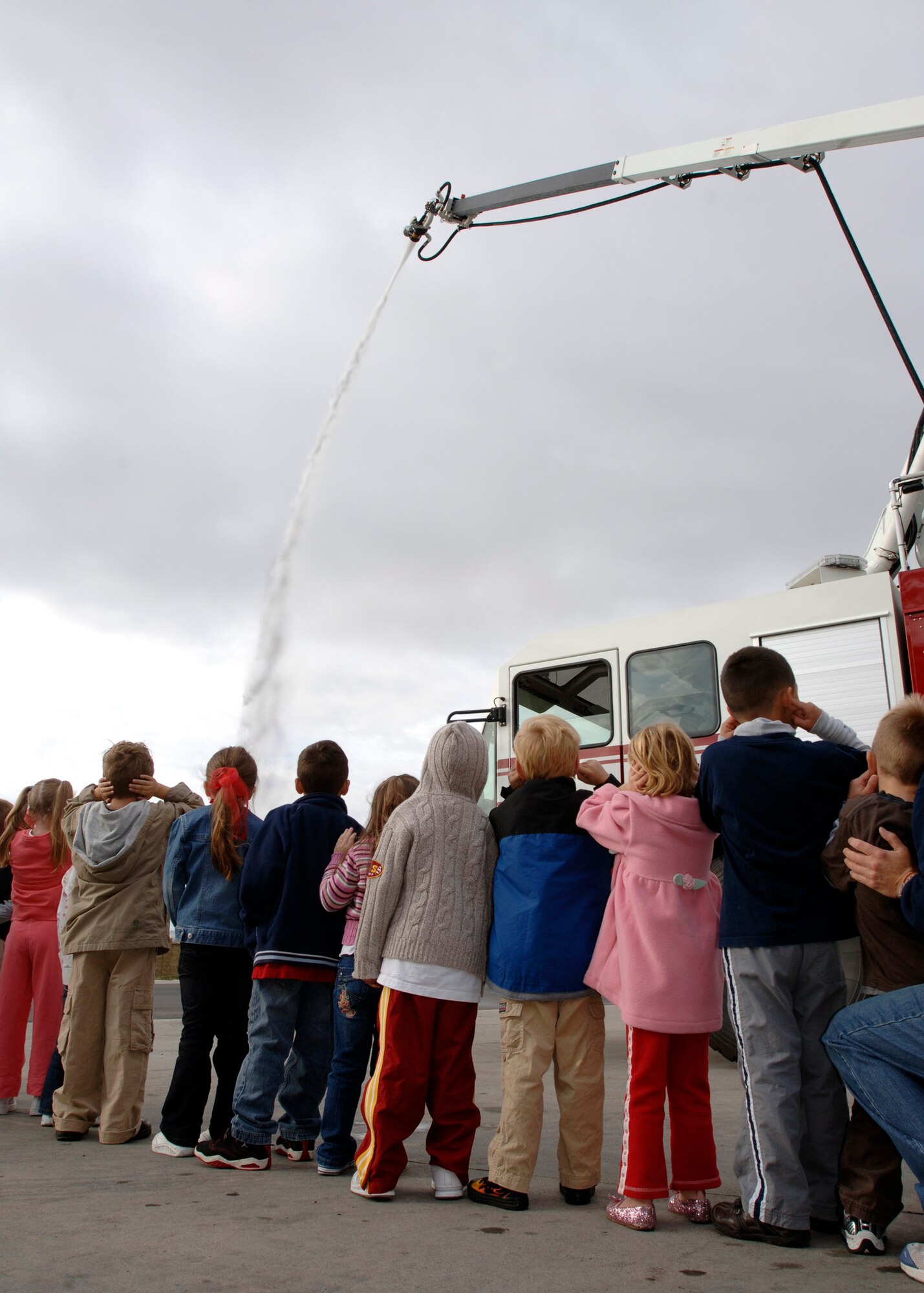 FAIRCHILD AIR FORCE BASE, Wash. – Kindergarten students plug their ears as a fire snozzle sprays water from above during an extinguishing simulation at the 92nd Civil Engineer Squadron fire department Oct. 3. The students were taught important safety precautions that would help them escape the fire without harm. (U.S. Air Force photo / Airman 1st Class Melissa Barnett)