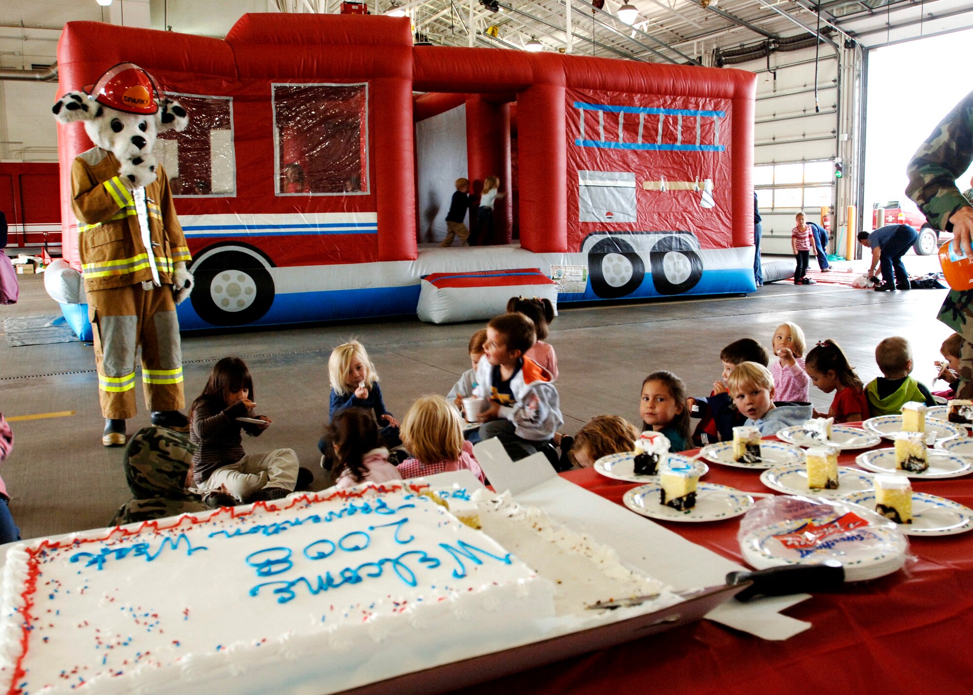 FAIRCHILD AIR FORCE BASE, Wash. – A kindergarten class from Michael Anderson Elementary School enjoys cake with Sparky the Fire Dog after a tour of the 92nd Civil Engineer Squadron fire station Oct. 3. A fire truck jumping castle, a fire truck water demonstration, and cake were provided to the fire department to begin Fire Prevention week. The cake was donated by the Fairchild Commissary. (U.S. Air Force photo / Airman 1st Class Melissa Barnett) 
