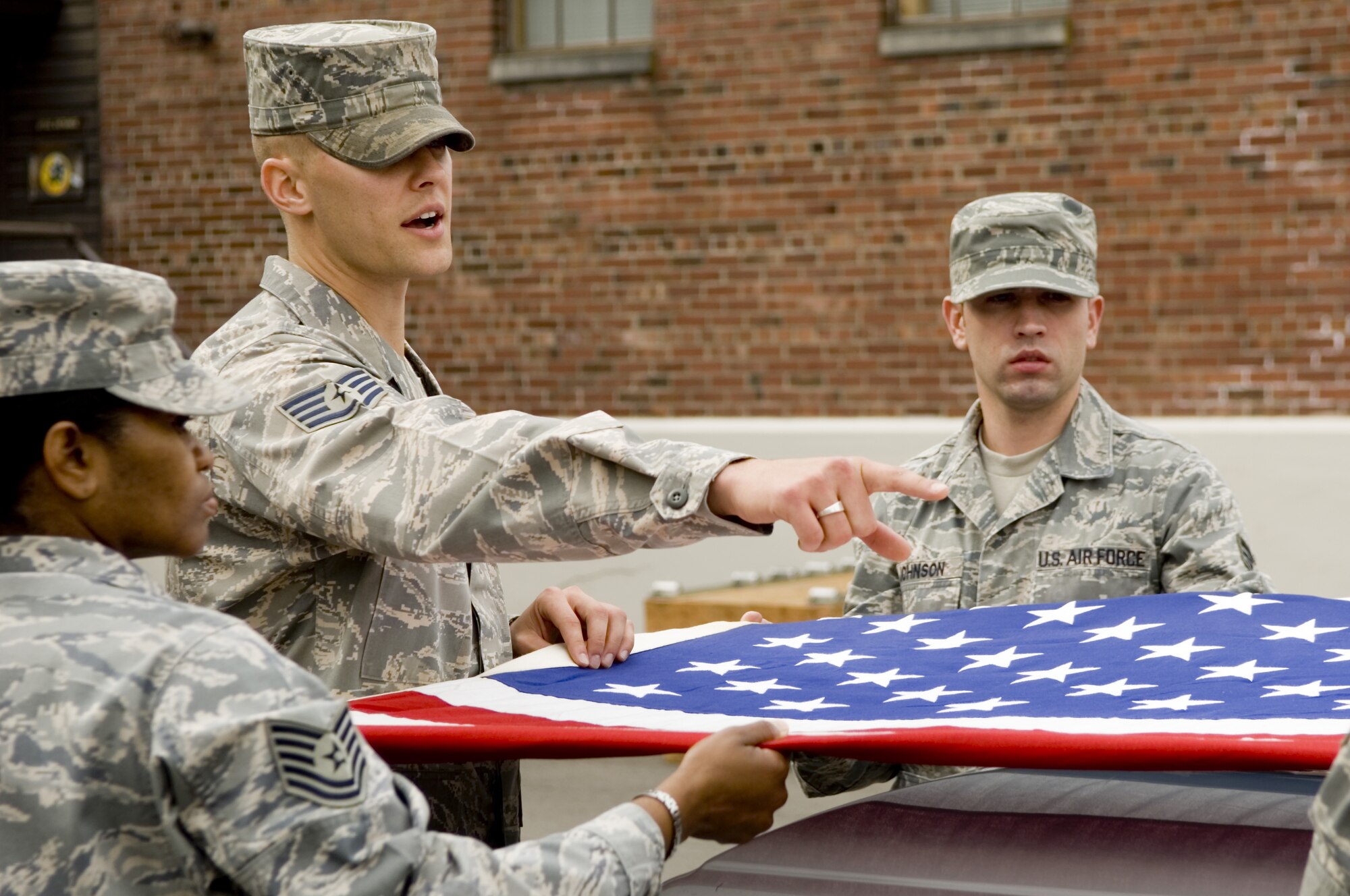 Staff Sgt. Alex Frizzo, U.S. Air Force Honor Guard formal training instructor, advises base honor guardsmen on proper flag-folding techniques during a reent training visit to McChord Air Force Base, Washington. (Photo courtesy of U.S. Air Force Honor Guard)