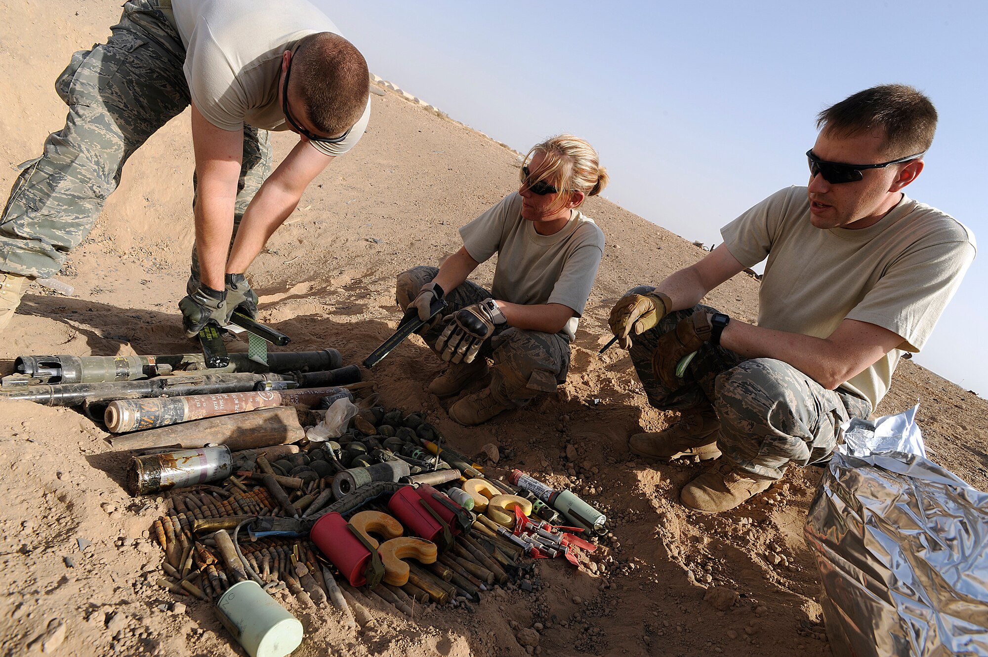 Senior Airman Craig Zehrbach, Staff Sgt. Mesa Anderson, and Tech. Sgt. Jason Mellor place C-4 explosives on a cache of ordnance at Joint Base Balad, Iraq, Oct. 8. The 332nd Expeditionary Civil Engineer Squadron Explosive Ordnance Disposal team periodically detonates unserviceable munitions that take up space in storage facilities. Zehrbach, an EOD journeyman, is deployed from Whiteman Air Force Base, Mo. His hometown is Cedar Rapids, Iowa. Anderson, an EOD technician, is deployed from Peterson Air Force Base, Colo. Her hometown is Montrose, Calif. Mellor, an EOD technician, is deployed from Dobbins Air Reserve Base, Ga. His hometown is Bethel Park, Pa. (U.S. Air Force photo/Airman 1st Class Jason Epley)