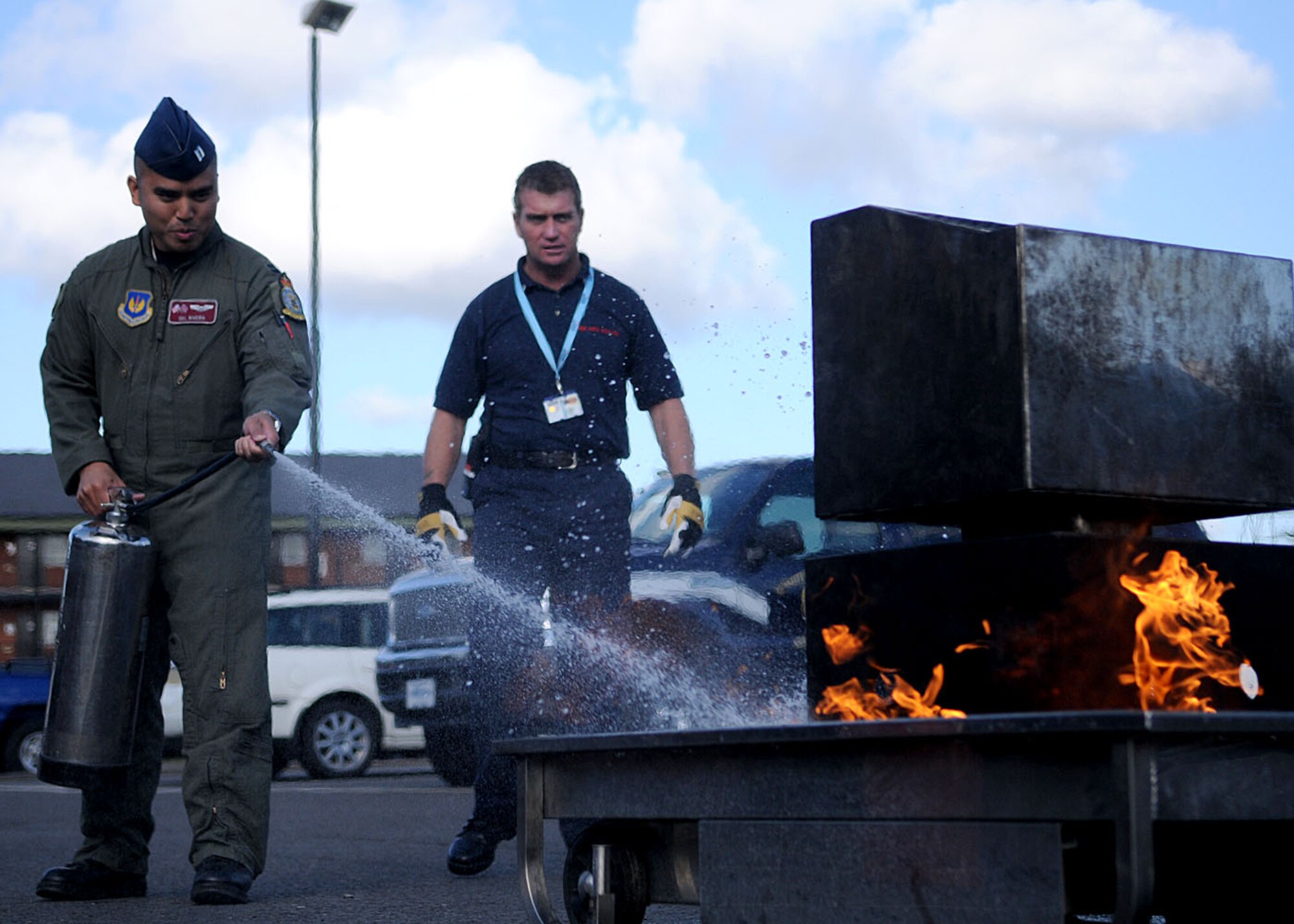 Capt. Del Rivera from the 100th Air Refueling Wing, extinguishes a fire in the Bob Hope Community Center parking lot, while Mr. Ken Cross, a Military Of Defence firefighter from the 100th Civil Engineering Squadron, keeps a watchful eye during the demonstration on Oct. 8, 2008, at RAF Mildenhall, England. The purpose of the extinguisher training was to give members hands on experience on how to safely put out a fire. The training was all part of “Fire Prevention Week” which ran Oct. 5 through 11 giving servicemembers and their families information on fire safety. (U.S. Air Force photo by Staff Sgt. Jerry Fleshman)