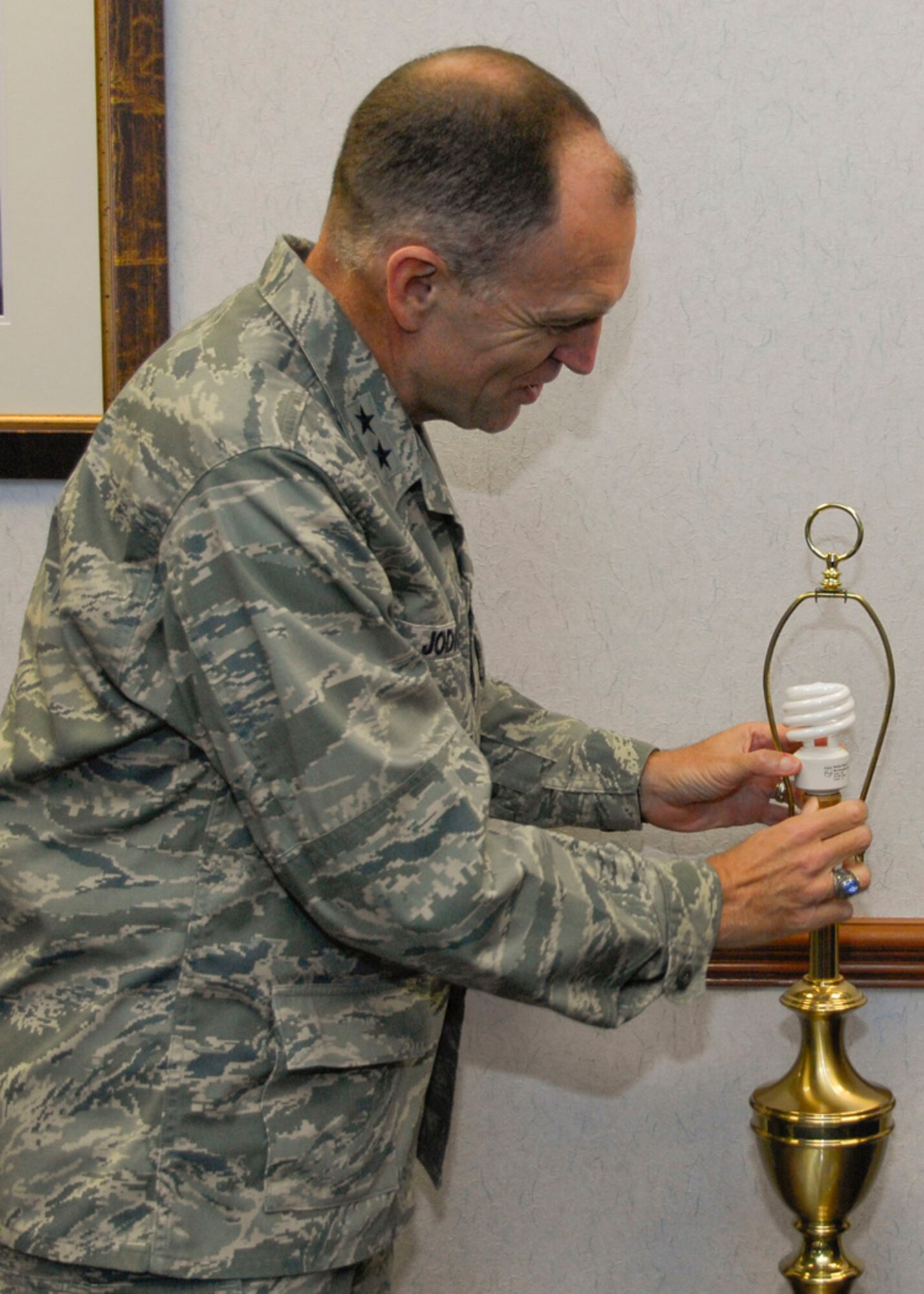 Maj. Gen. Ralph J. Jodice II, Air Force District of Washington commanding general, replaces an incandescent light bulb with a compact fluorescent light bulb in his office at Andrews Air Force Base, Md. AFDW is participating in Operation Change Out, a jointly-sponsored effort between the Defense Department and the U.S. Department of Energy that encourages everyone connected with a military installation to reduce energy usage.