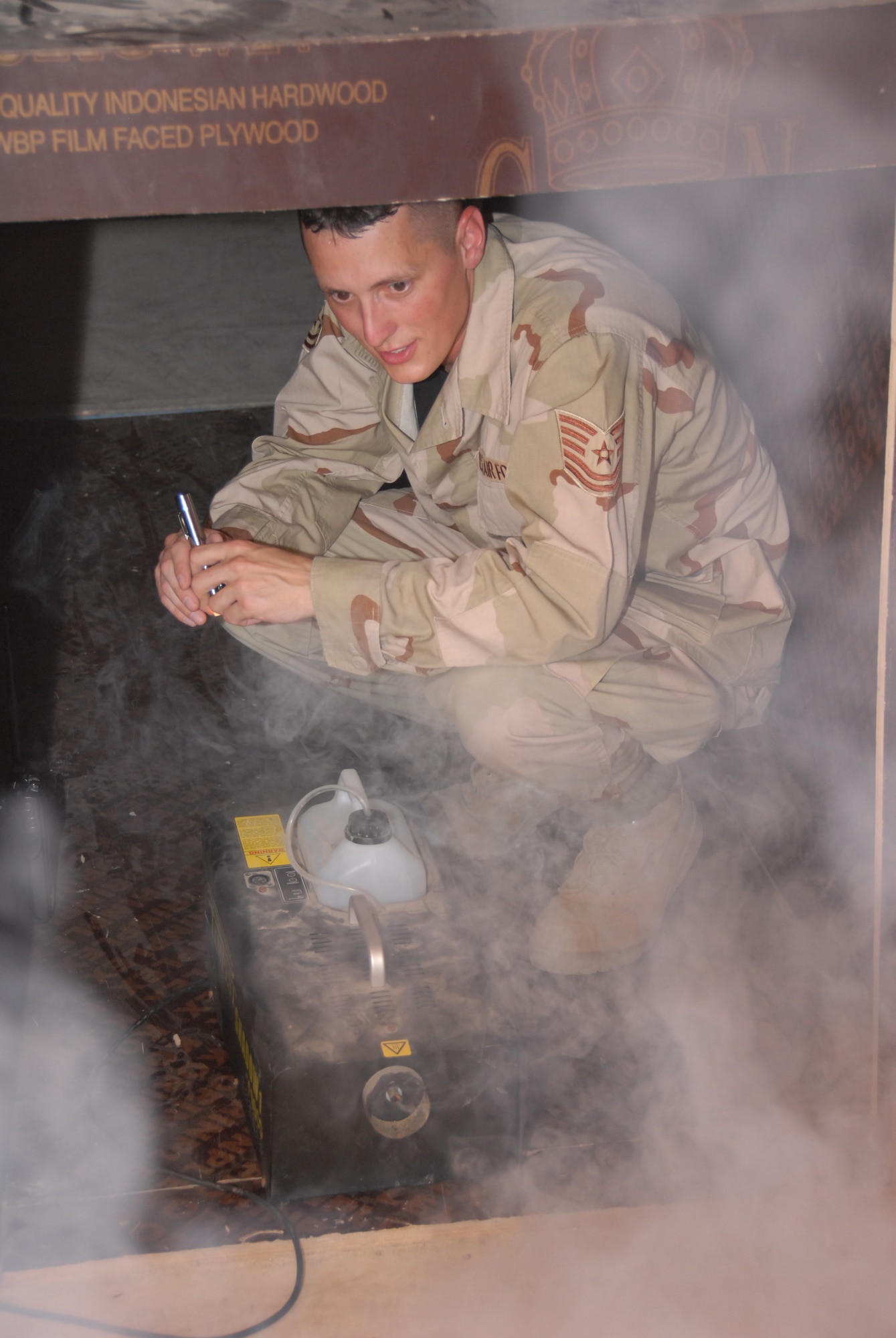 SOUTHWEST ASIA--Tech. Sgt. Jack Hartman starts the smoke machine in preparation for a smokehouse training exercise here. The smokehouse trainer was opened to allow fellow Airmen from the base to don firefighter equipment and work in zero-visibility conditions.  Sergeant Hartman is the training and logistics officer for the 380th Civil Engineer Squadron's Fire Protection Flight. He is deployed from McGuire Air Force Base, N.J. and resides in New Egypt, N.J.(released/photo by 1st Lt. Michael Frye)