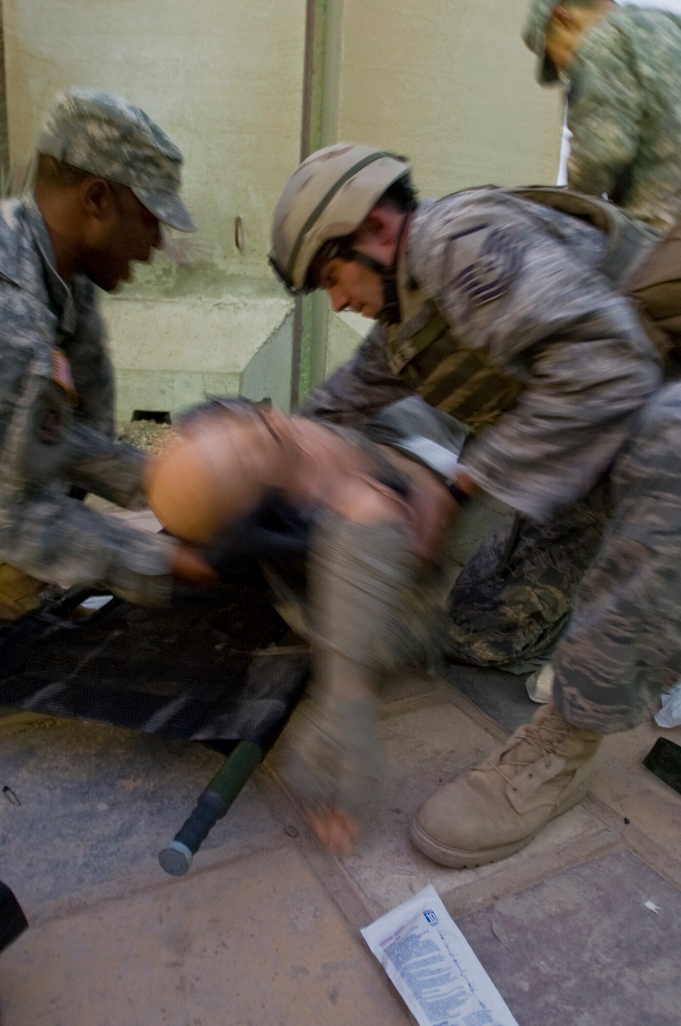 ALI BASE, Iraq -- Army Staff Sgt. Derrick Sterling, 894th Quartermaster Company convoy patrolman, and Master Sgt. Peter Winetroub, 407th Air Expeditionary Group anti-terrorism officer, place an "injured victim" on a litter Oct. 9, 2008. Army and Air Force members attended a combat lifesaver course, for the final exam each class team ran through a scenario putting the skills they learned to the test. Sterling is deployed from 894th QM Co., a reserve unit based in Jackson, Miss. Winetroub is deployed from Shaw Air Force Base, S.C. (U.S. Air Force photo/Senior Airman Christopher Griffin) 