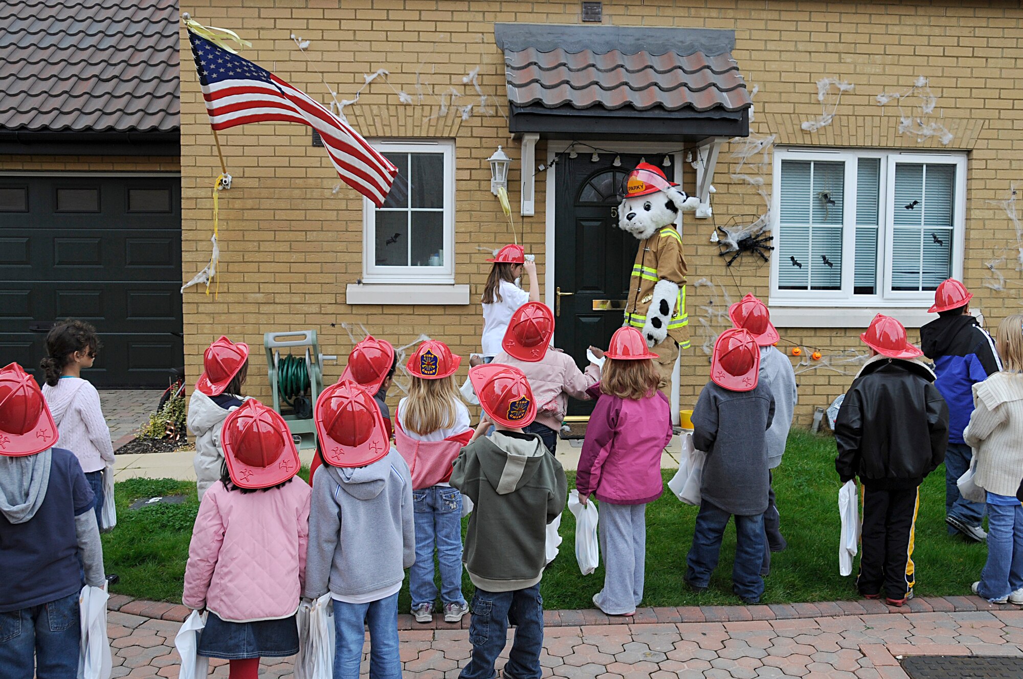 Sparky the fire dog walks door to door, with children from the youth center, handing out information and treats for Fire Prevention Week at RAF Lakenheath, England, Oct. 6. The effort was a community service effort of the children from the youth center as part of their 4-H club activity and in support of the Fire Prevention Week celebration. (U.S. Air Force photo by Senior Airman Brian J. Ellis)