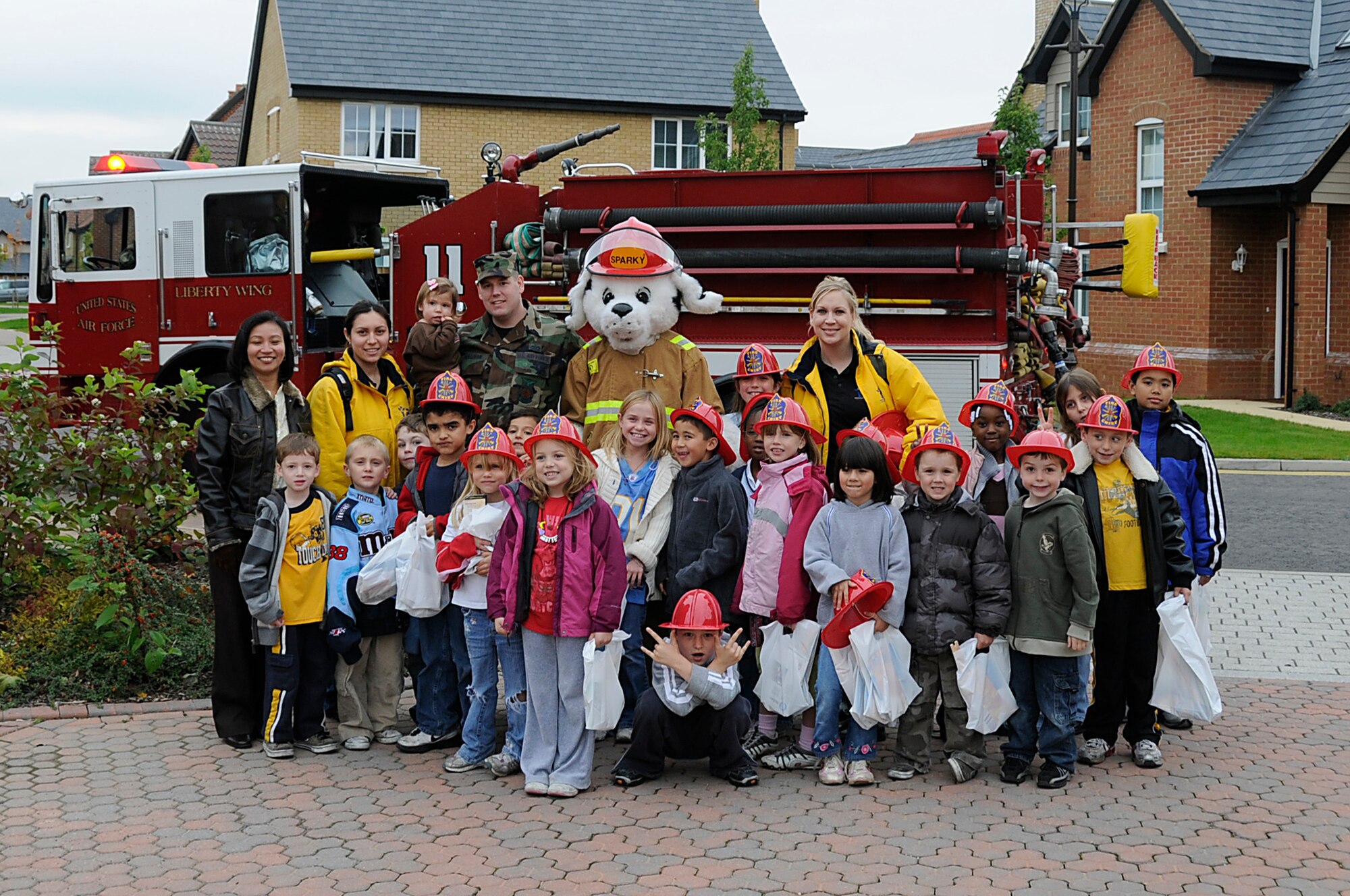 Children from the 48th Services Squadron Youth Center pose for a group photo with Sparky the fire dog during Fire Prevention Week at RAF Lakenheath, England, Oct. 6. In the spirit of Fire Prevention Week, children went door to door with Sparky handing out information to bring awareness to the base community. (U.S. Air Force photo by Senior Airman Brian J. Ellis)