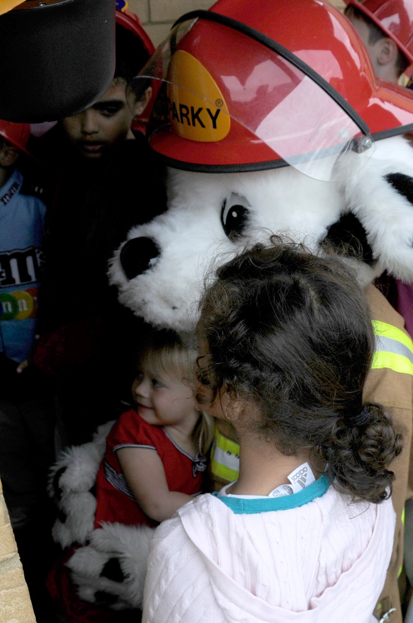 Sparky the fire dog gives a hug to Taylor Elkins during Natioanl Fire Prevention Week at RAF Lakenheath, England, Oct. 6. Taylor ran into Sparky's arms when the door opened as the rest of the children from the youth center crowded around. Sparky and children from the youth center were going door to door handing out information and treats as part of their 4-H club activity for community service. (U.S. Air Force photo by Senior Airman Brian J. Ellis)