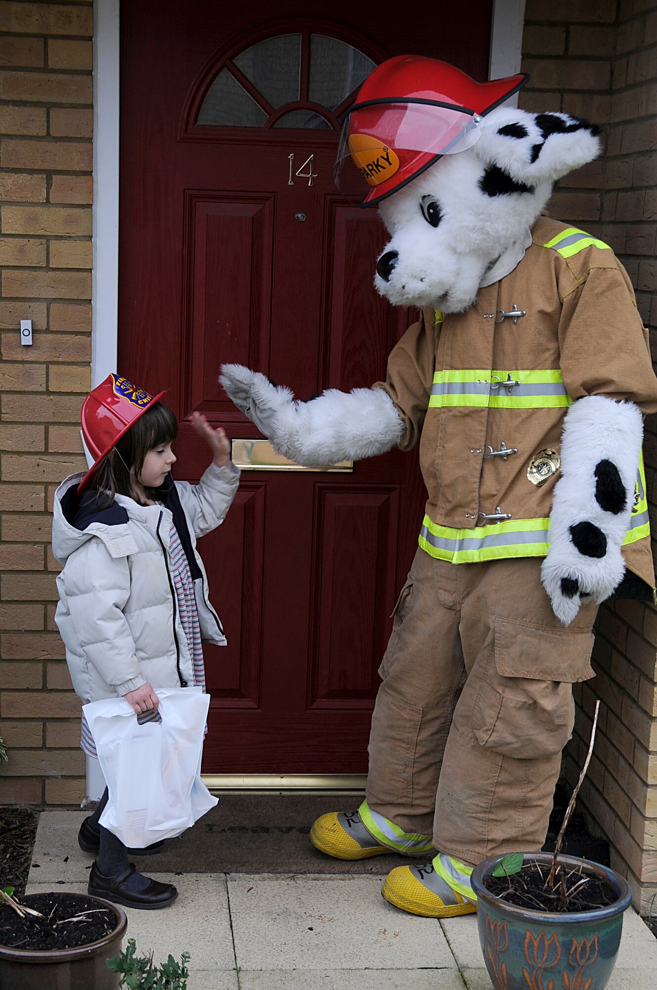 Sparky the fire dog gives a high five to Isabella Hendrix, 5, after a job well done during Fire Prevention Week at RAF Lakenheath, England, Oct 6. Isabella was one of many children from the youth center here helping Sparky hand out fire prevention information to the local community. (U.S. Air Force photo by Senior Airman Brian J. Ellis)