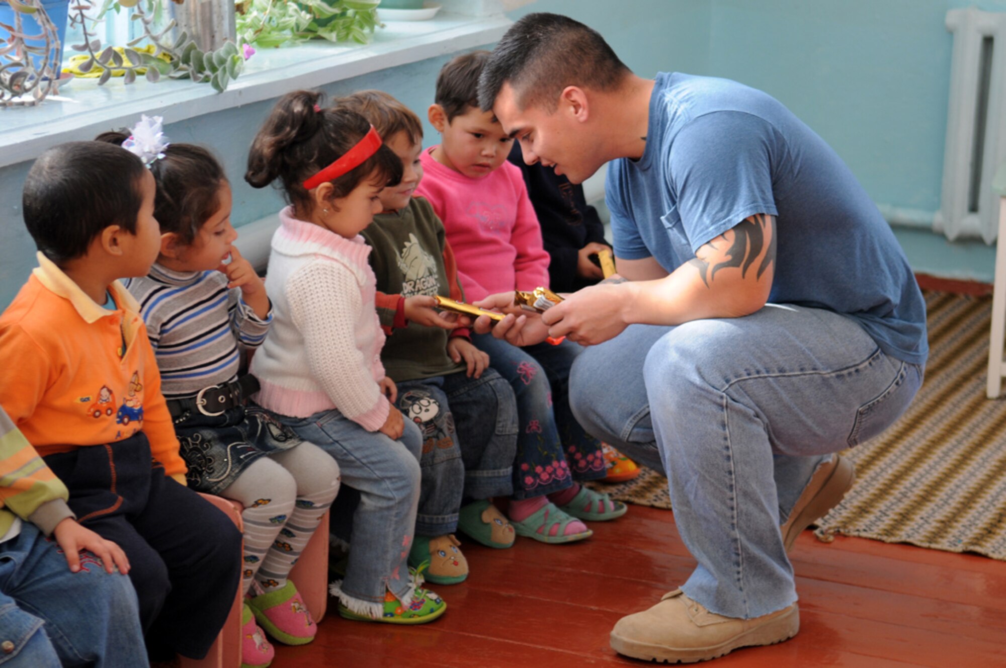 Staff Sgt. Brandon Arenibar, 376th Expeditionary Operations Group, hands out candy bars to the children at Vasilievika Elementary School, Oct. 7. Together the 376th Air Expeditionary Wing Staff and Operations Group have supported the school since 2004, pulling together donations, pooling skills such as painting and carpentry and just spending time with the kids. (Air Force photo / Senior Airman Ruth Holcomb)