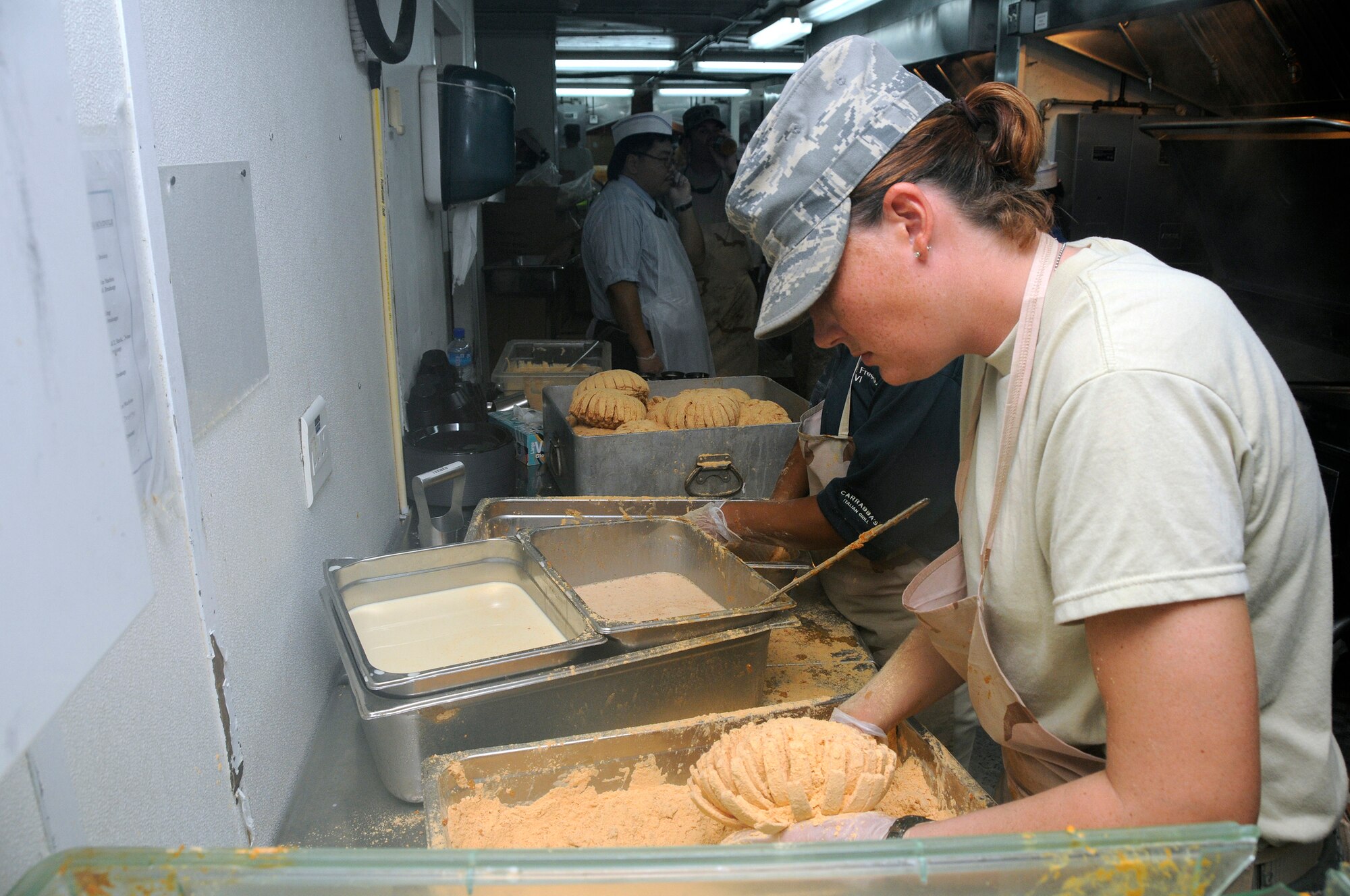 Airman 1st Class Amy Dunn-Watkins, 379th Expeditionary Force Support Squadron, prepares a Bloomin' Onion for frying by applying breading October 9, 2008. The Bloomin' Onion is breaded, then fried with technical support from employees of the Outback Steakhouse at an undisclosed air base in Southwest Asia.  The Outback brought in food and expertise in a show of support for U.S. troops supporting Operations Iraqi and Enduring Freedom and Joint Task Force-Horn of Africa.  (U.S. Air Force photo by Tech. Sgt. Michael Boquette/Released)