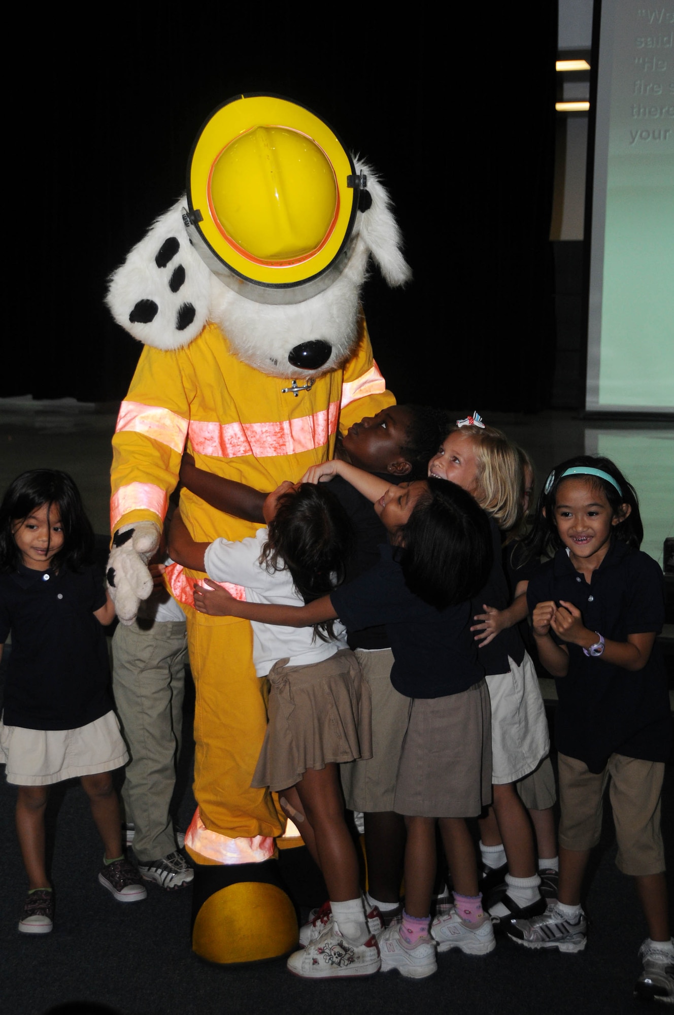 ANDERSEN AIR FORCE BASE, Guam - Airman Colton Balthazor, 36th Civil Engineer Squadron firefighter, receives smiles and big hugs from Andersen's Elementary School students during Fire Prevention Week here Oct. 9. The character "Scruffy" is used to entertain and inform children on the importance of fire safety. (U.S. Air Force photo by Senior Airman Sonya Croston)