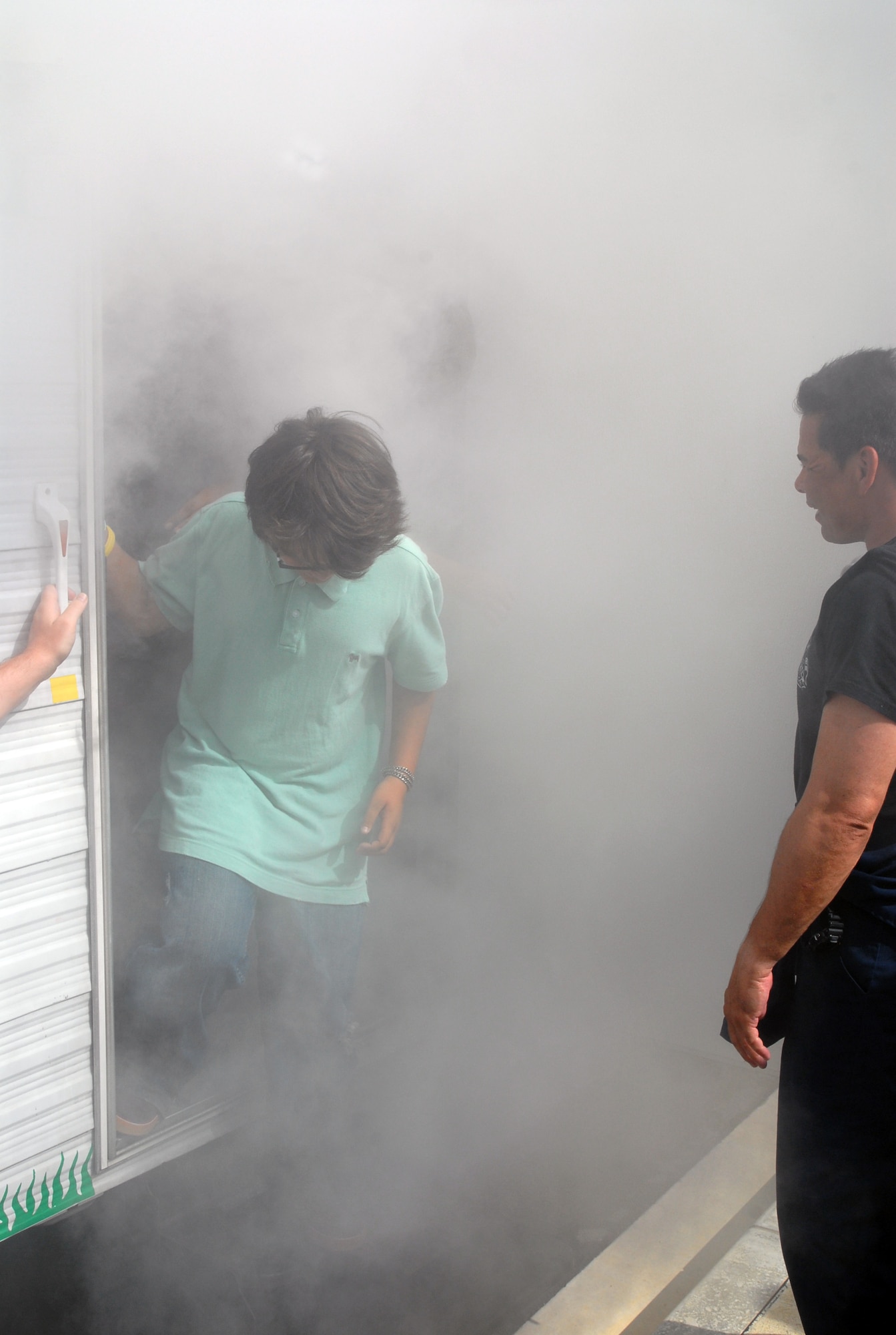 Students from Ryukyu Middle School attempt to rescue a mannequin from the Kadena Fire Department's "Smoke House" Oct. 9.  The trailer simulates a two-story building filled with smoke and shows students the difficulty of finding their way around in alow vision environment. (U.S. Air Force photo/Staff Sgt. Christopher Marasky)
