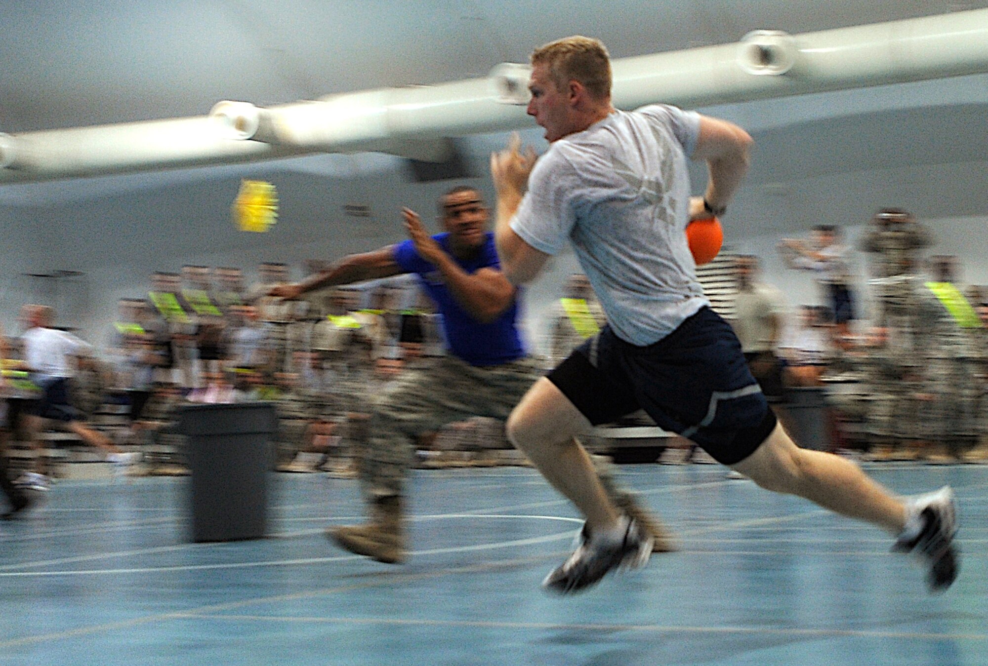 A contender competes in the Powerball event during an American Gladiators competition at Joint Base Balad, Iraq, Oct. 7. Powerball is an event in which contenders have to score points by getting balls into scoring pods within a time limit. Each contender is assigned a Gladiator whose aim is to stop them scoring by tagging them with both hands. Both the Air Force and the Army competed together against the American Gladiators, who are touring bases in the U.S. Central Command area of responsibility. (U.S. Air Force photo/Airman 1st Class Jason Epley)