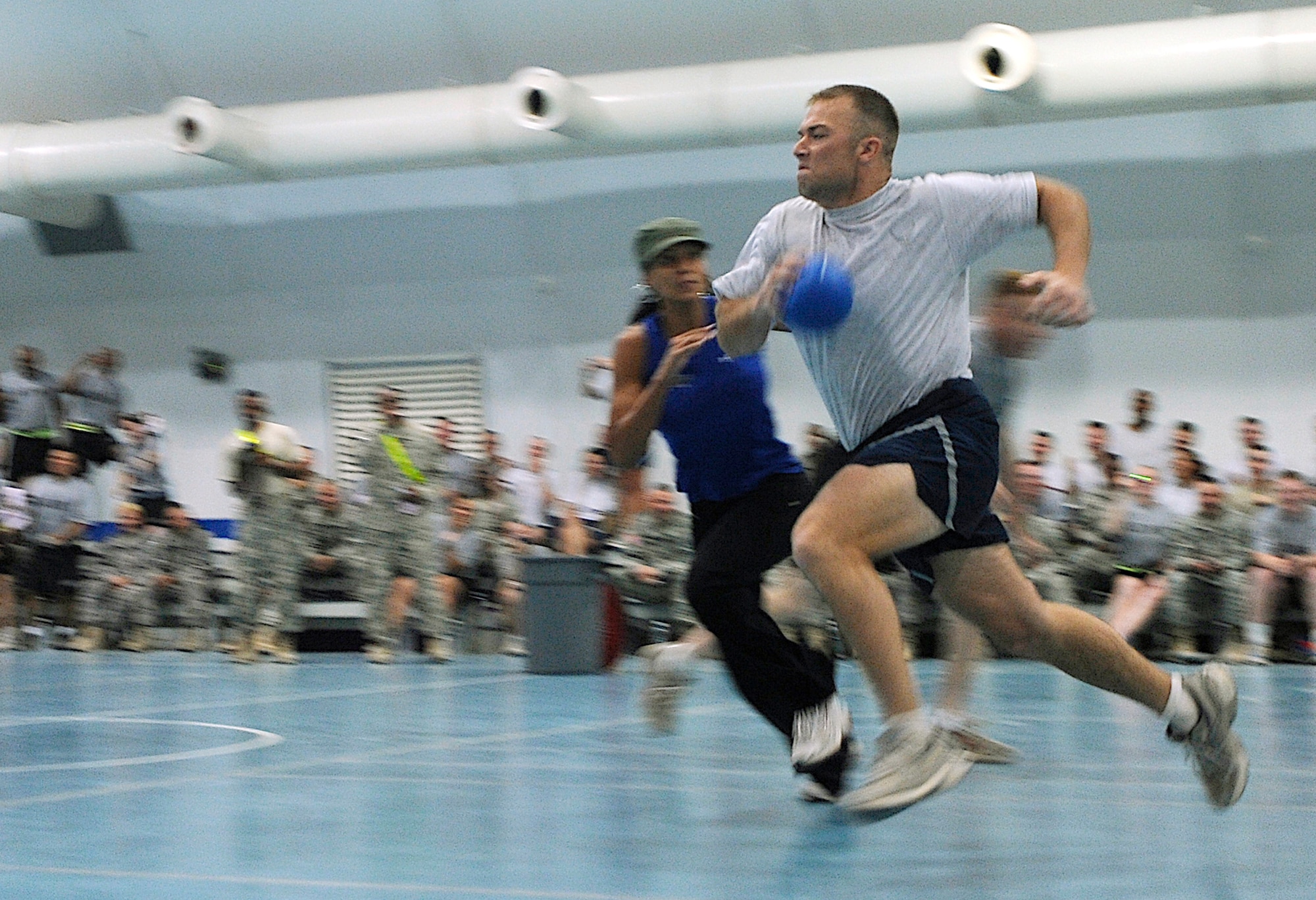 A contender competes in the Powerball event during an American Gladiators competition at Joint Base Balad, Iraq, Oct. 7. Powerball is an event in which contenders have to score points by getting balls into scoring pods within a time limit. Each contender is assigned a Gladiator whose aim is to stop them scoring by tagging them with both hands. Both the Air Force and the Army competed together against the American Gladiators, who are touring bases in the U.S. Central Command area of responsibility. (U.S. Air Force photo/Airman 1st Class Jason Epley)