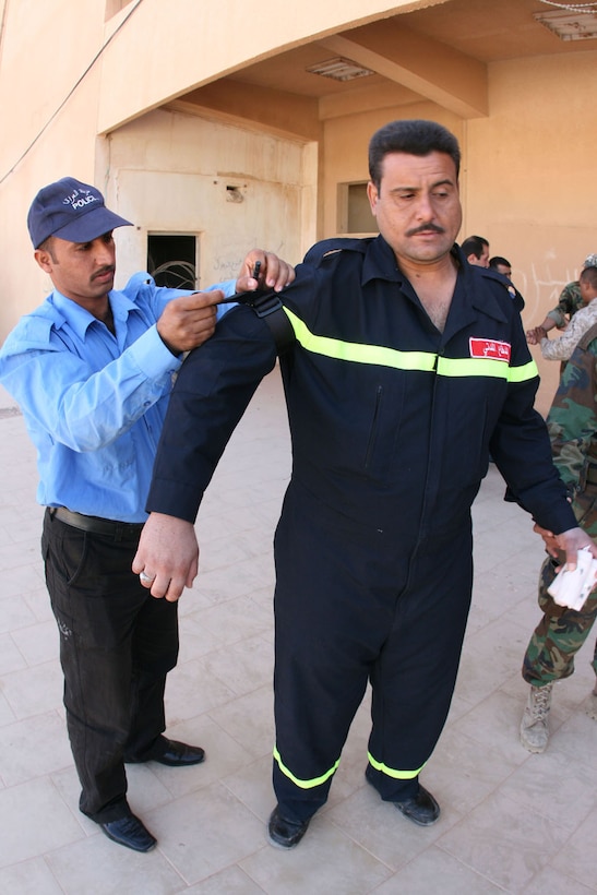 An Iraqi border police officer (left) applies a tourniquet to the arm of an Iraqi fireman during a first aid class taught by Marines and sailors with the Trebil Port of Entry Transition Team Oct. 11. Trebil is located in western al-Anbar province on Iraq's border with Jordan.::r::::n::