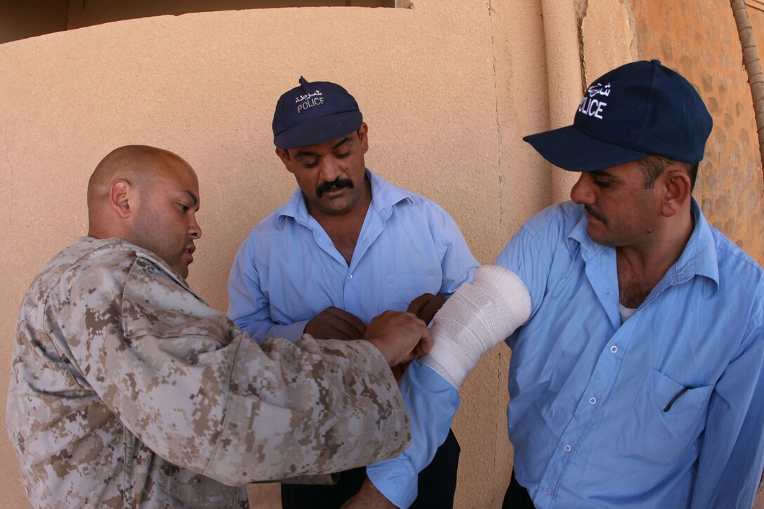 Under the mentorship of Sgt. Victor F. Virgen, maintenance chief, Trebil Port of Entry Transition Team, Iraqi police officers practice putting pressure dressings on simulated wounds during a training exercise Oct. 11 at Trebil, Iraq.  Marines and sailors with the POETT taught fundamental first aid skills to the Iraqi troops manning the border port. ::r::::n::