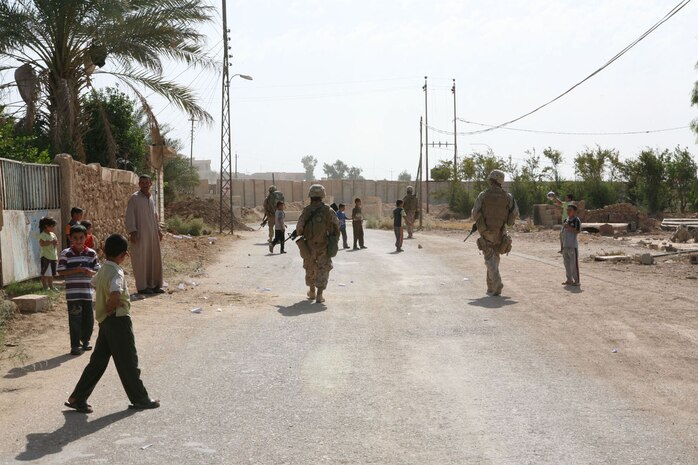 Marines from Provisional Rifle Platoon 3, Regimental Combat Team 5, pass a group of children playing soccer in Rawah, Iraq, Oct. 20.  The Marines provide security over watch in the town by going on security patrols.  The platoon, which is comprised of both infantry and non-infantry Marines, is also in charge of two traffic control points near Rawah.::r::::n::