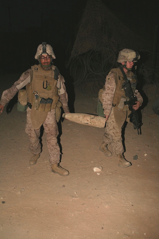 Cpl. Alex Raymundo, left, a rifleman and data technician, and Sgt. Justin Sweda, a squad leader and administration clerk, both with Provisional Rifle Platoon 3, Regimental Combat Team 5, carry a 155 mm artillery shell in from a patrol along the northern bank of the Euphrates River in Rawah, Iraq, Oct. 15. The patrols coming out of Traffic Control Points 3 and 4, manned by PRP-3 Marines, look for any suspicious activity that would disrupt the security of Rawah.::r::::n::