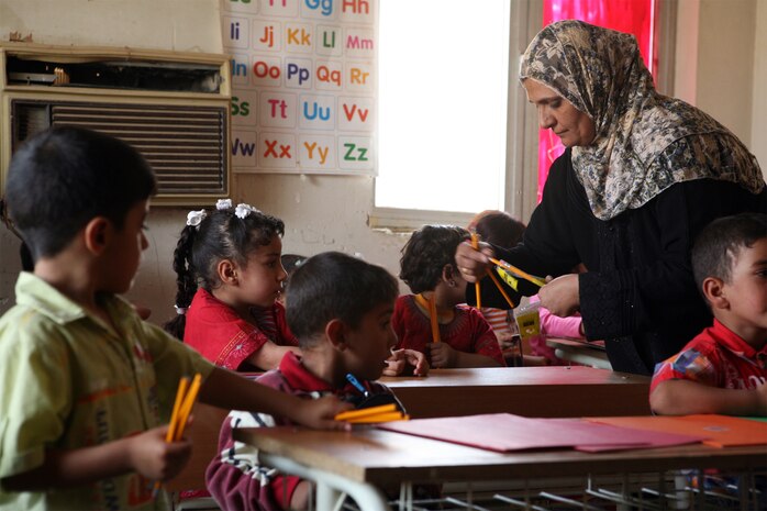 A teacher at one of three Tri-City schools passes out school supplies to her students, recently. Army Cpl. Greg Farrell, an assistant team leader with a Psychological Operations (PSYOP) team in direct support of Task Force 1st Battalion, 2nd Marine Regiment, Regimental Combat Team 1, worked with his father Kevin Farrell, the Iraqi Project Director for the Southeast Denver Rotary Club, since April to arrange the collection and delivery of the supplies to Iraqi schools.